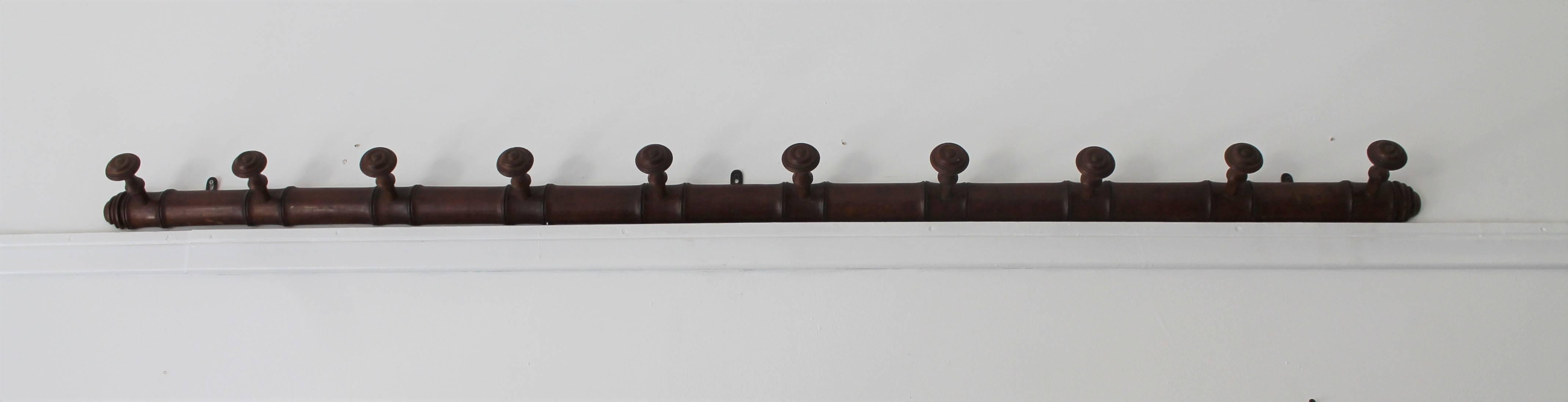 This early handmade peg rack is from a tack shop and was used as a horse bridle rack. The condition is very good with the original metal hangers on the back side.