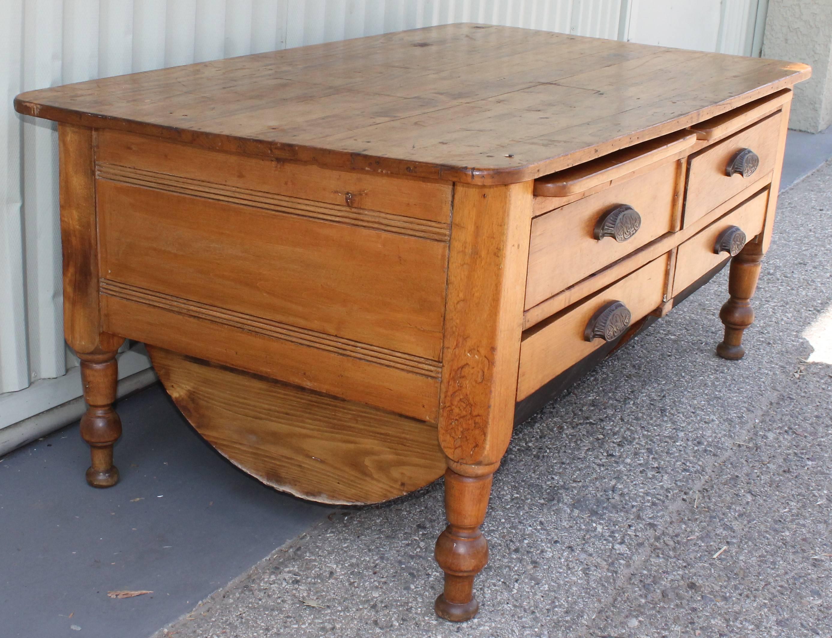 This cool table has four drawers and the two bottom drawers are pull-out bins. On top of the two drawers are slide out writing drawers. This old kitchen work table has the original cast iron drawer pulls or hardware. This coffee table is in pine and
