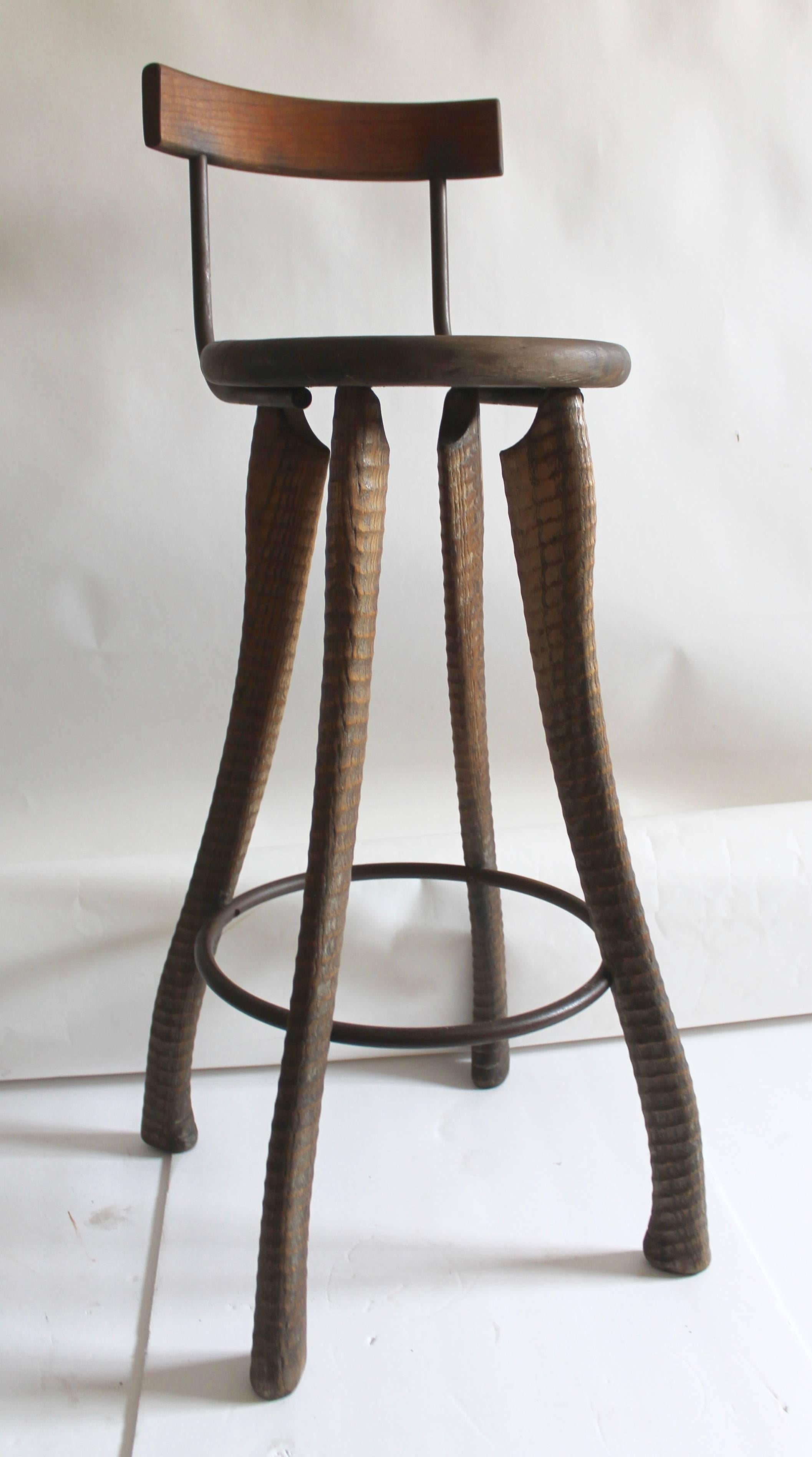 This folky handmade bar stool and all hand-carved legs. The iron footrest matches the iron rungs on the back of the seat attached. Take special notice to the details in the hand-carved legs. The condition is very good and comfortable.