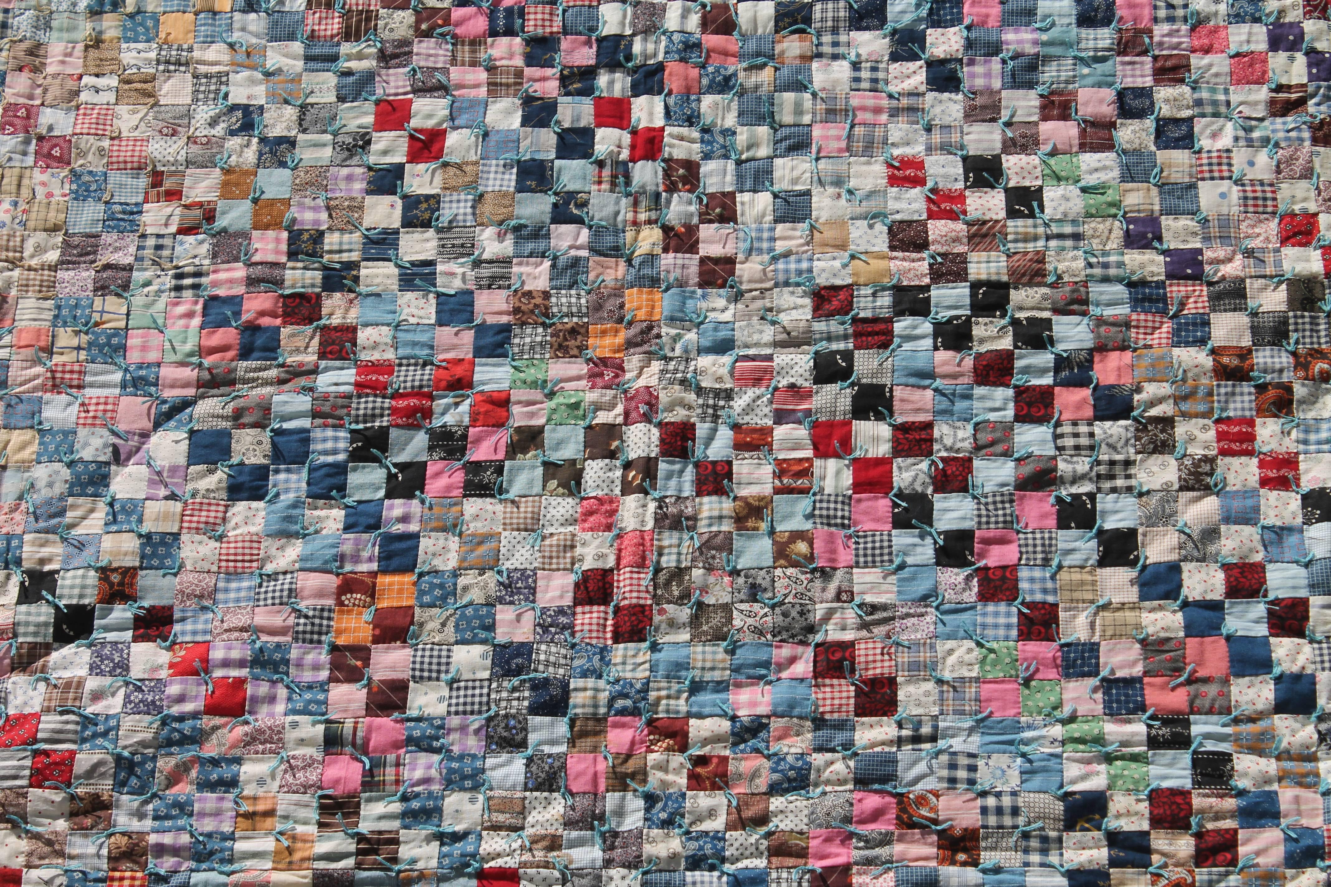 This finely pieced postage stamp quilt is in mint condition and vibrantly executed. This large size quilt would fit a queen or king size bed. This is a pieced and tied quilt.