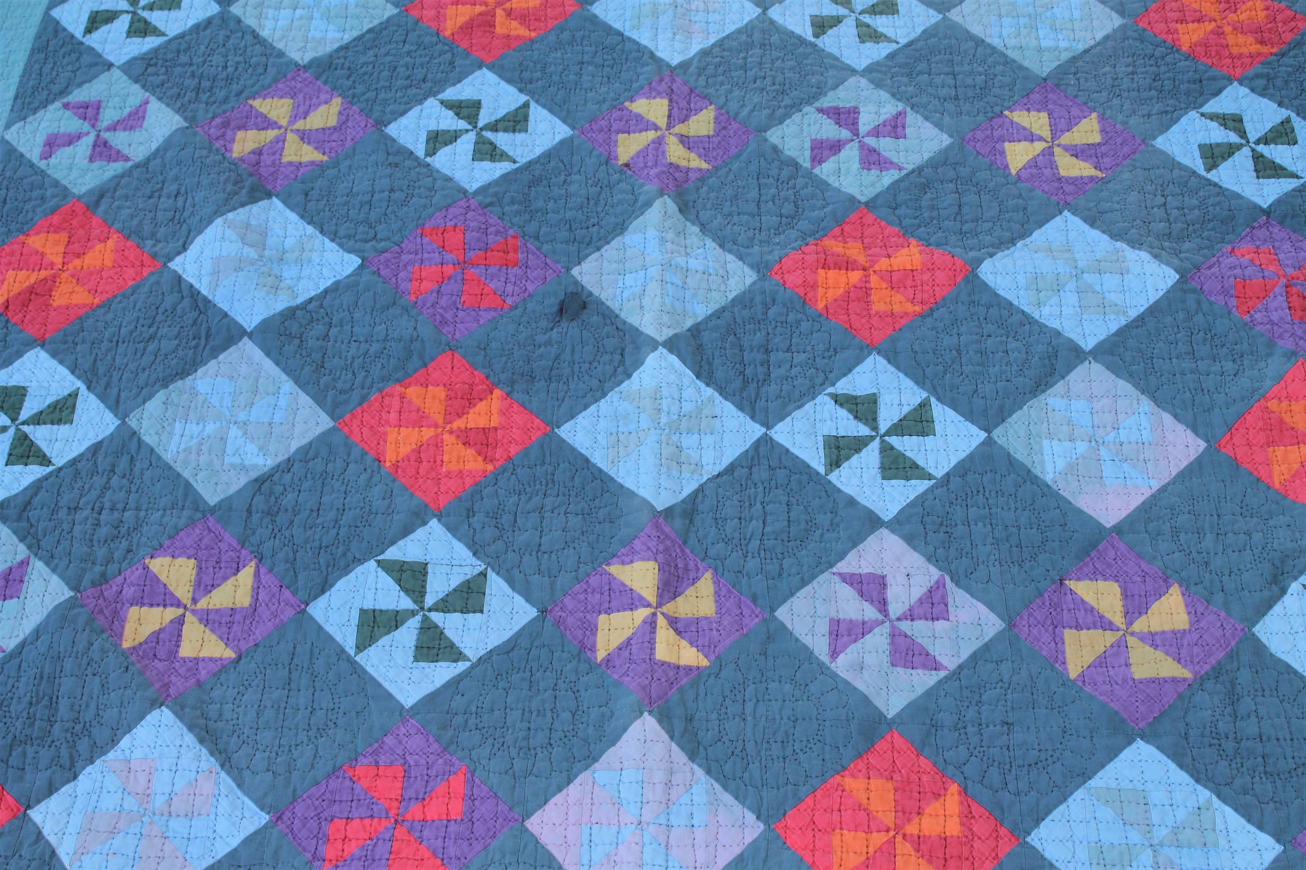 This mid-western Amish pin wheel quilt is in good condition with one minor circular repair. The piece work and quilting is in good condition. The quilt has overall muted colors. It has a triangular border.