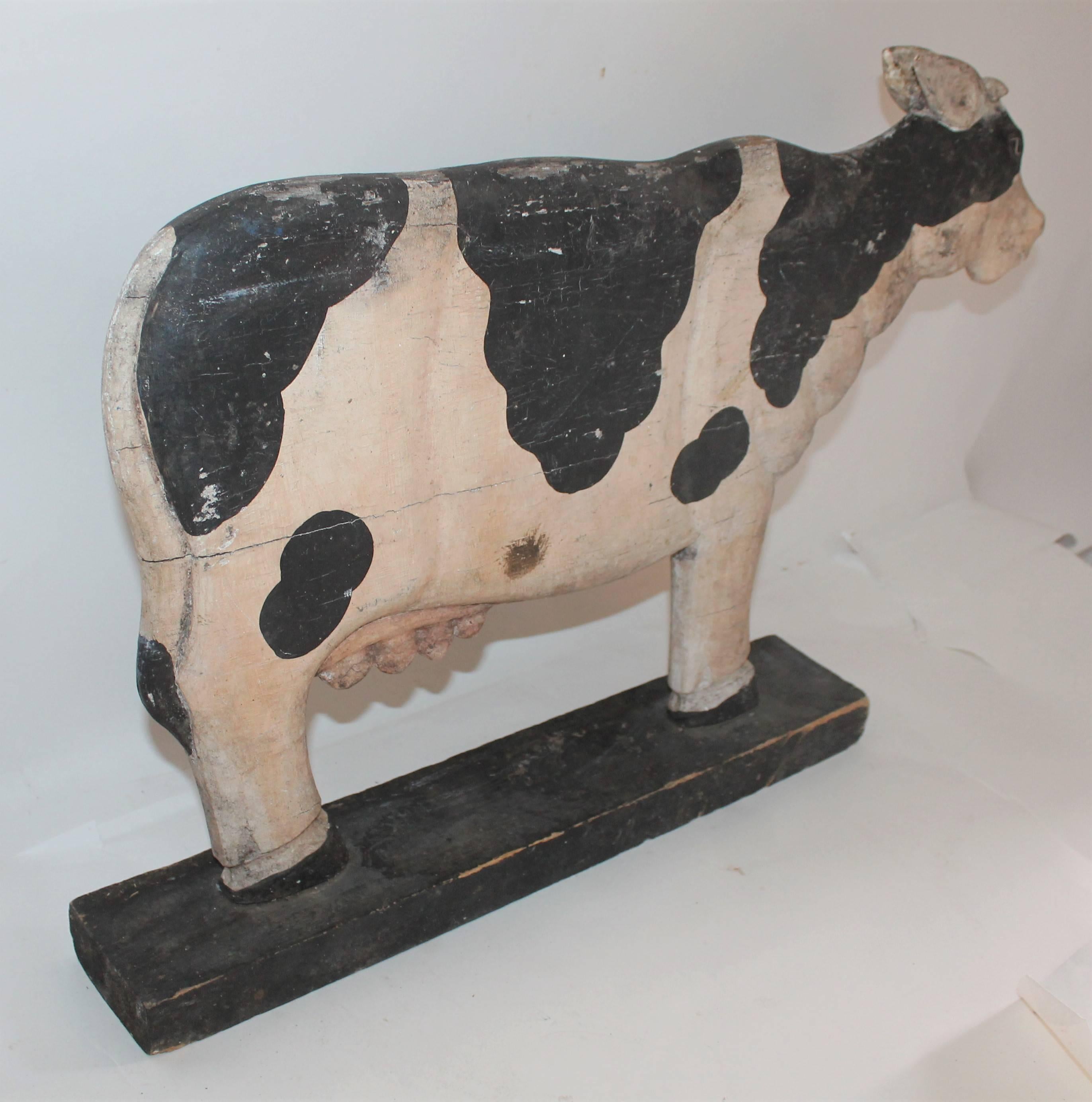 This hand-carved and painted folky standing cow trade sign was probably used on a counter or window in a dairy farm. The black base is original to the Folk Art carved cow. There is paint loss and wear consistent from age and use and likely it was