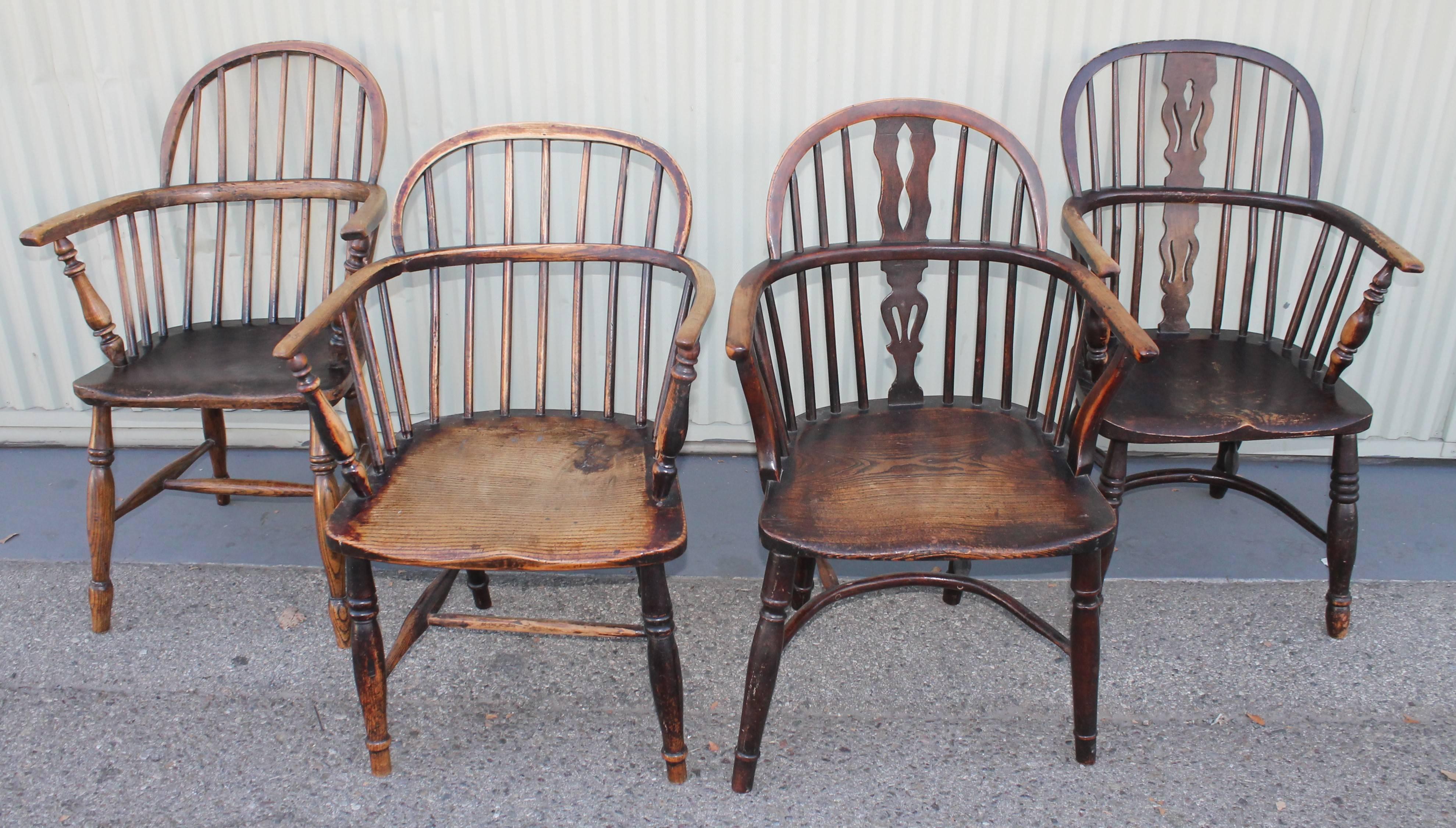 Collection of four Windsor chairs from England. All four chairs are slightly different. Fantastic patina and all in sturdy condition. Minor old small repairs here and there. Wear consistent from age and use.