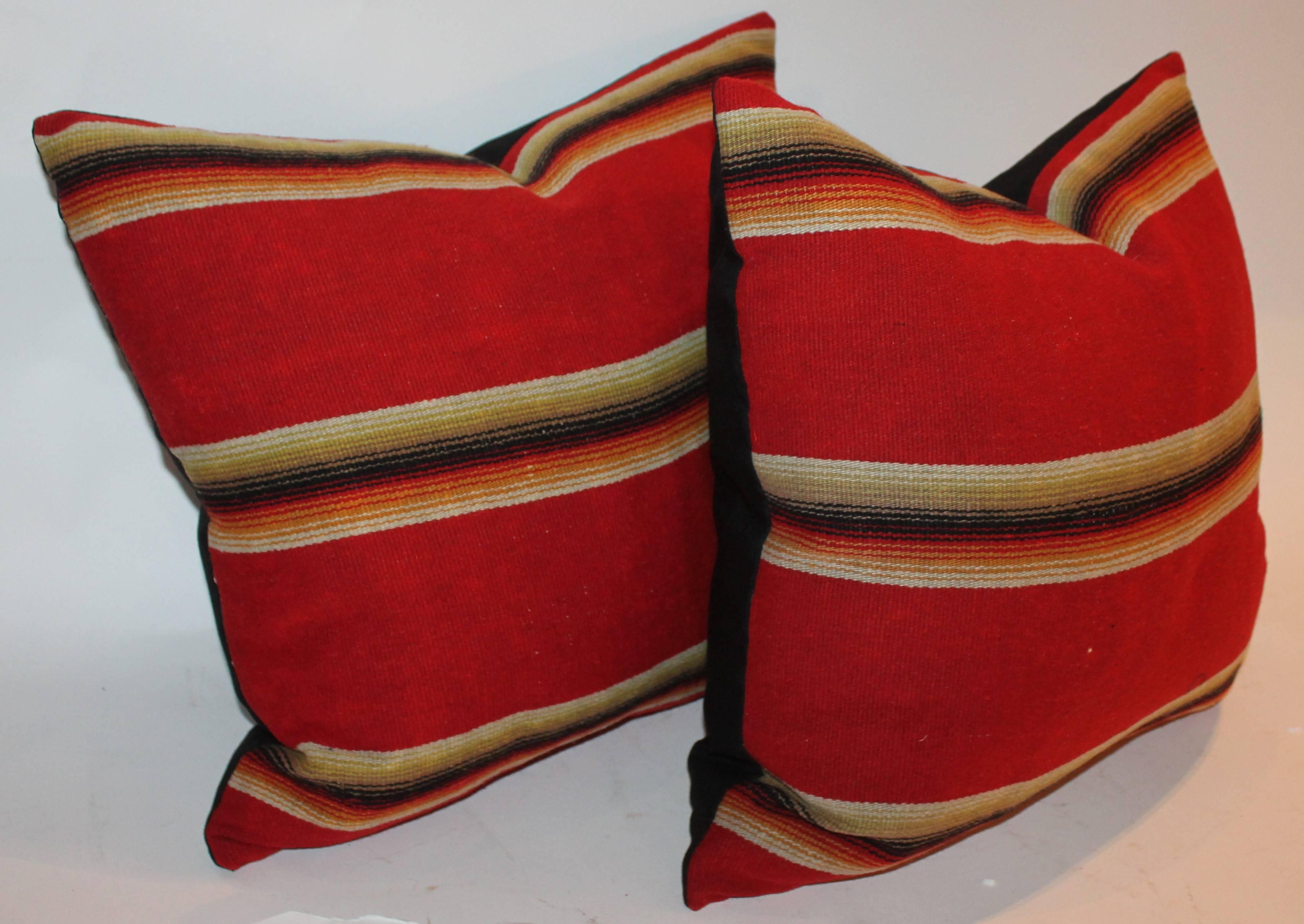 Wool serape Indian sunset pillows in fine condition. The backing is in black cotton linen. Sold as a matching pair.