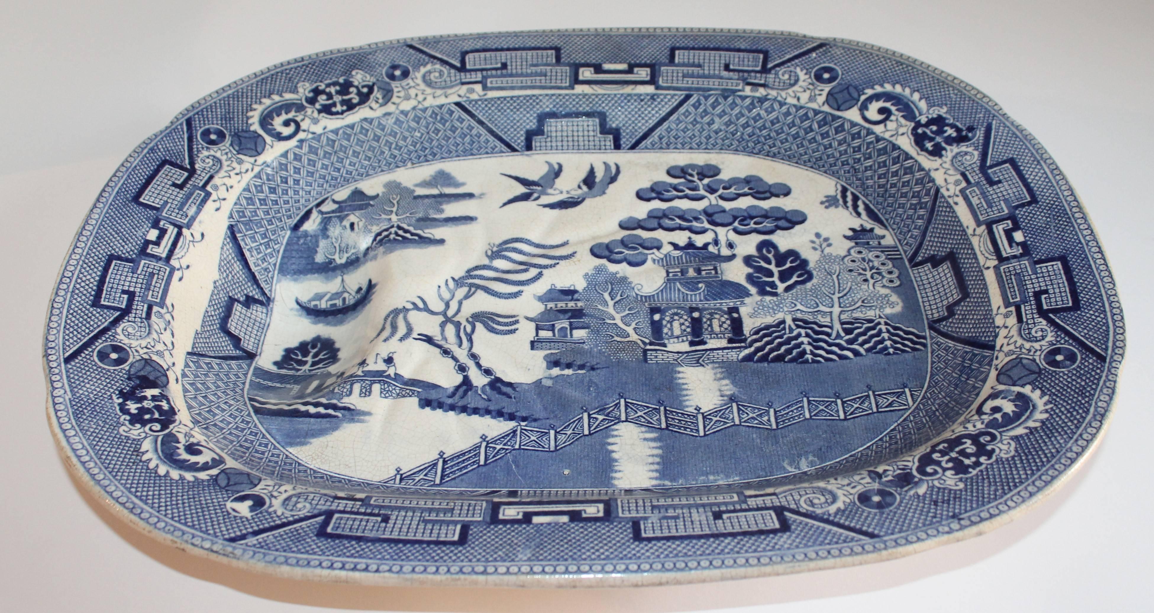 Early 19th century English Blue Willow Meat platter with the drain built in the base. This large tray is unsigned and is footed. The condition is very good with crazing and age spots on the reverse.