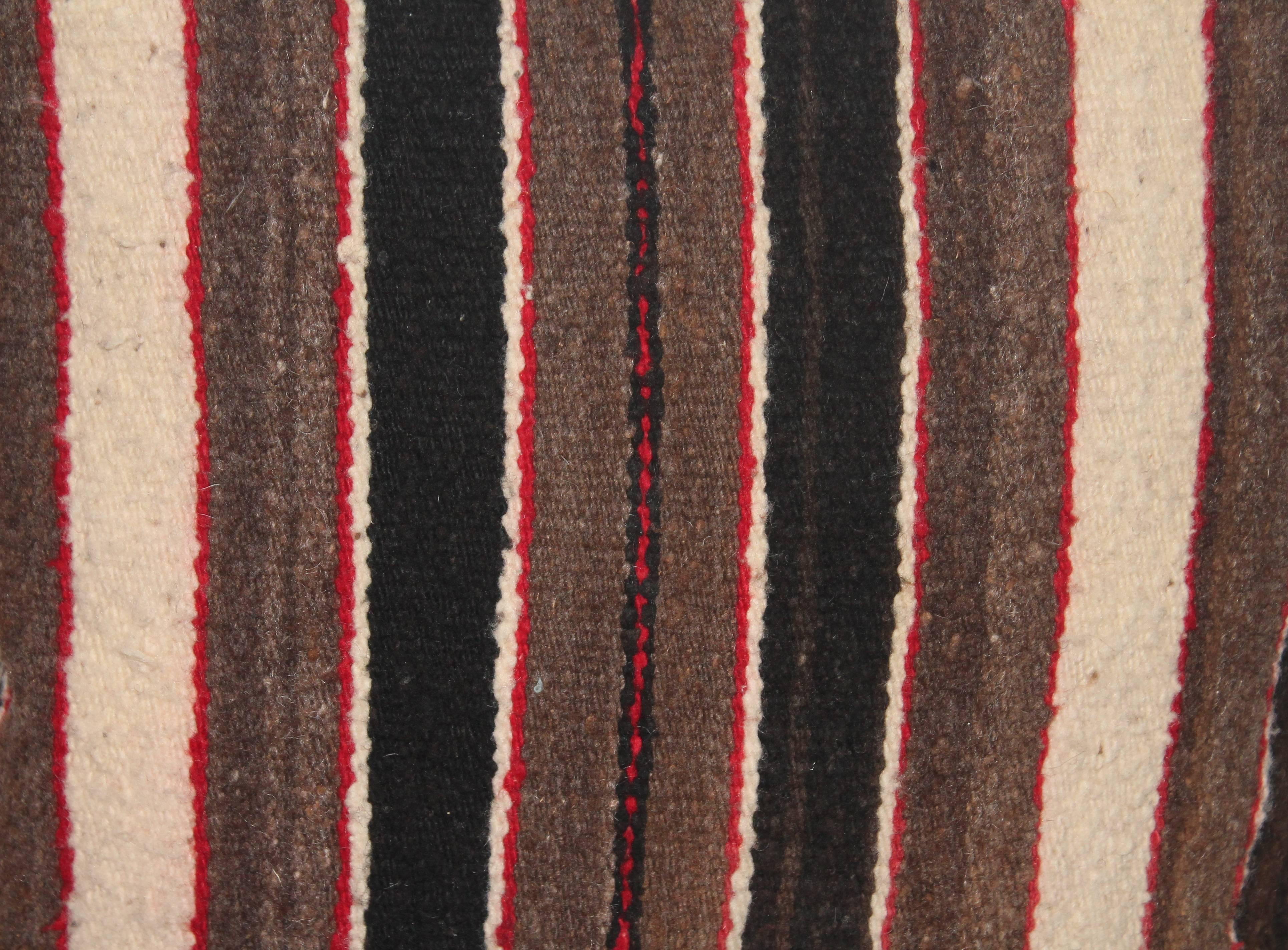 This fantastic striped handwoven saddle blanket was probably made for a child given the smaller size. It has the original corner ties and is in fine condition. This weaving pillow has a black cotton linen backing.