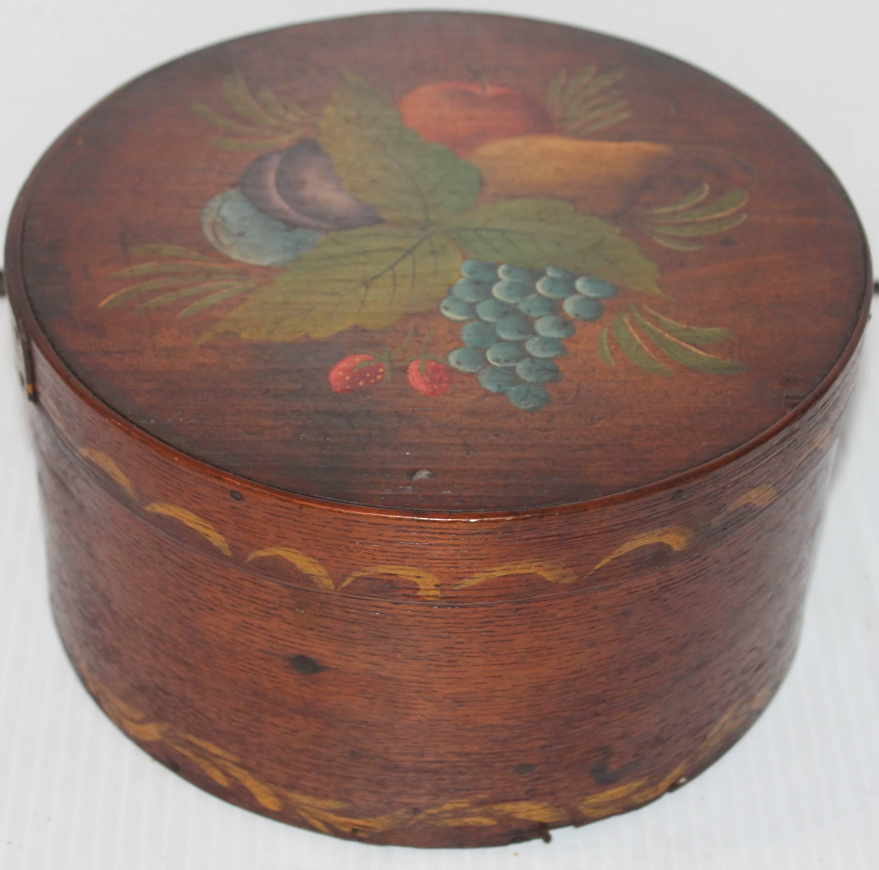 This early handmade and painted fruit decorated and swag painted border on lid and base pantry box. The condition or surface of the paint is very good. This is very similar to the fruit decorated chairs or settles from Pennsylvania or New England.