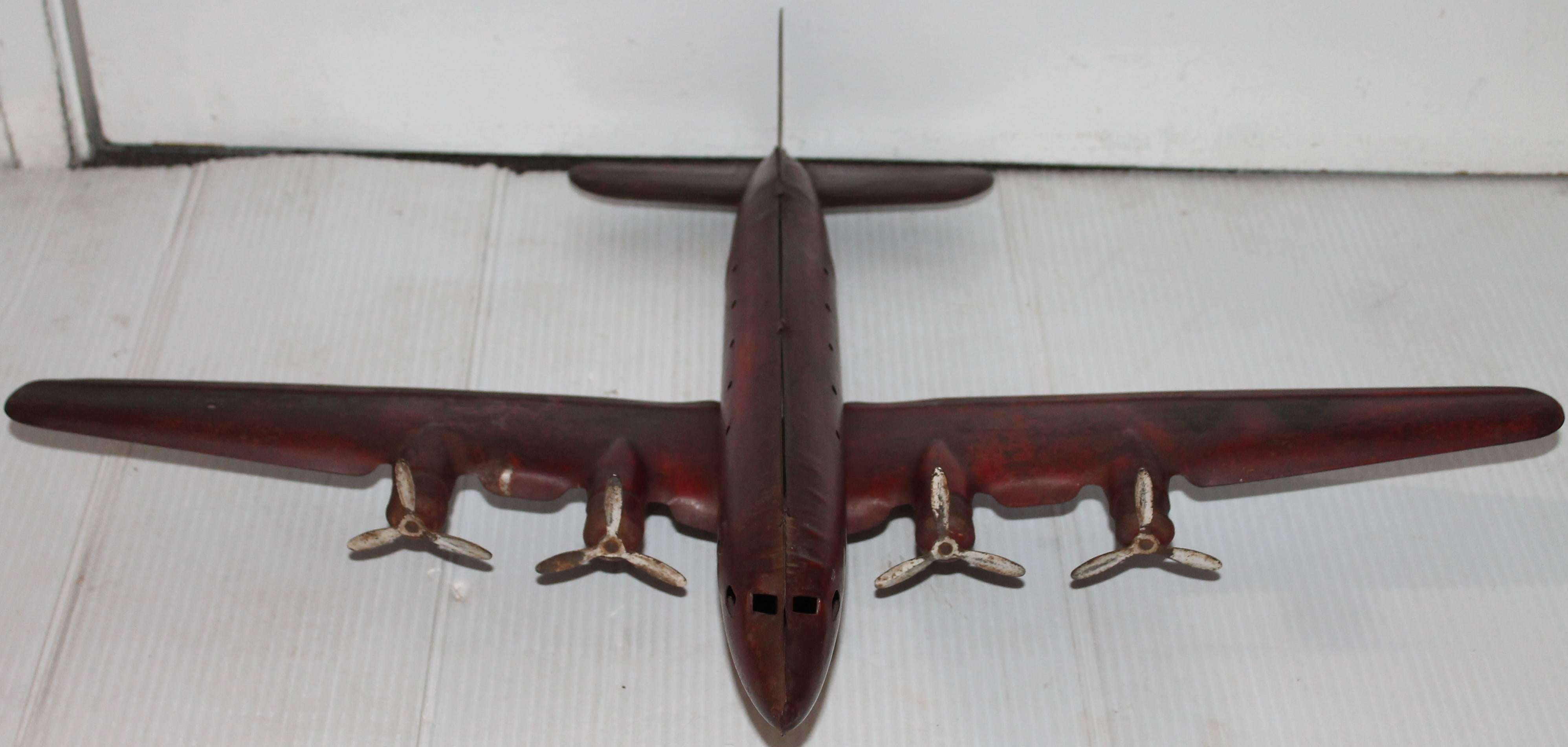 This unusual painted tin airplane is in very good working condition. It is painted AA in black letters and NC2100. The wheels are in original wood and original tin propellers. The surface is all original and undisturbed.
