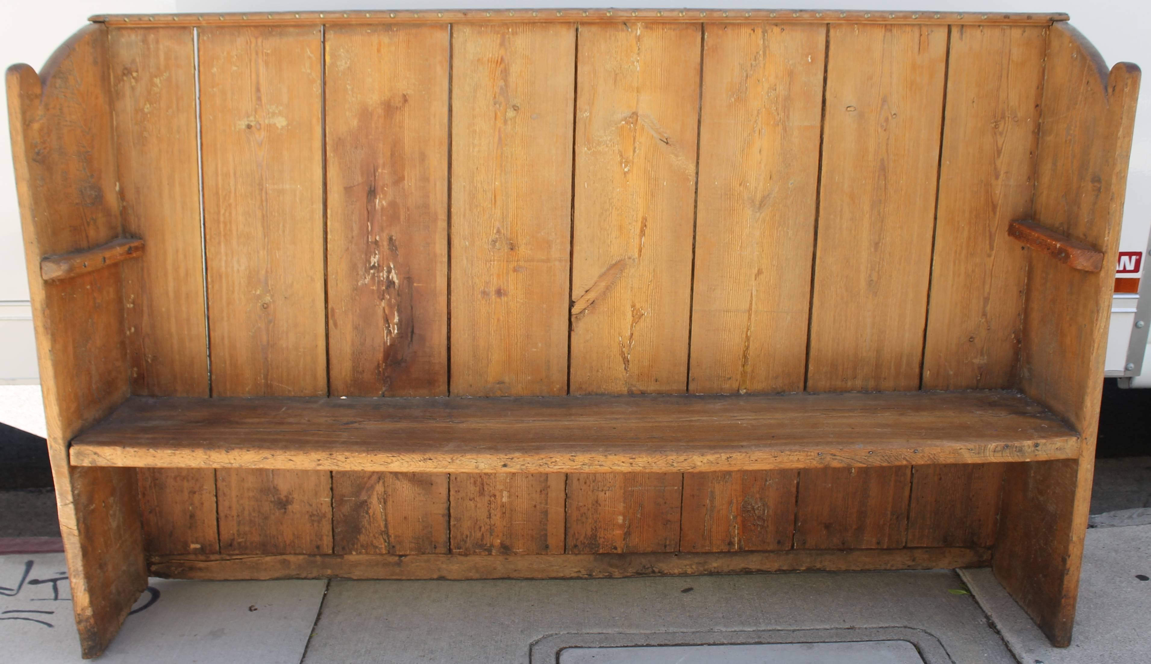 This early rustic settle is made with wide plank boards and early handmade nails. It is in sturdy as found condition with a wonderful aged patina. There is also original brass tacks on the top trim molding. Great for a country or western setting.
