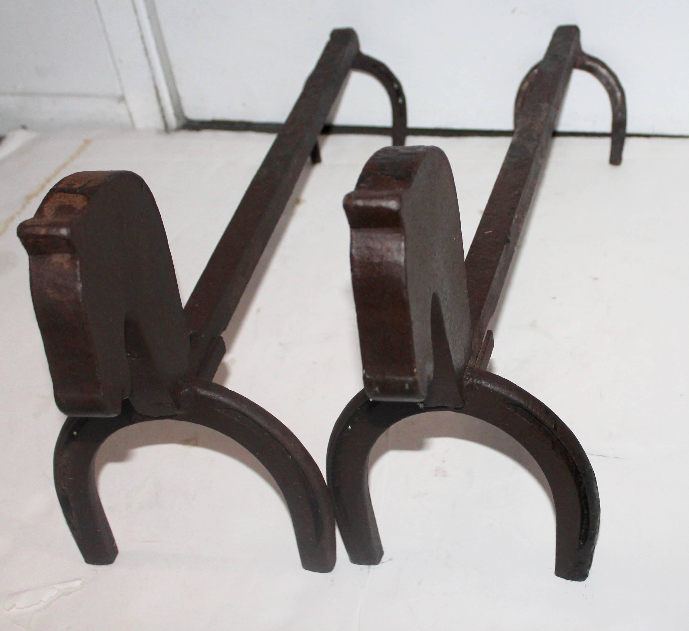 This early pair of handmade cast iron horse shoe and horse head andirons. This pair is in wonderful as found condition.