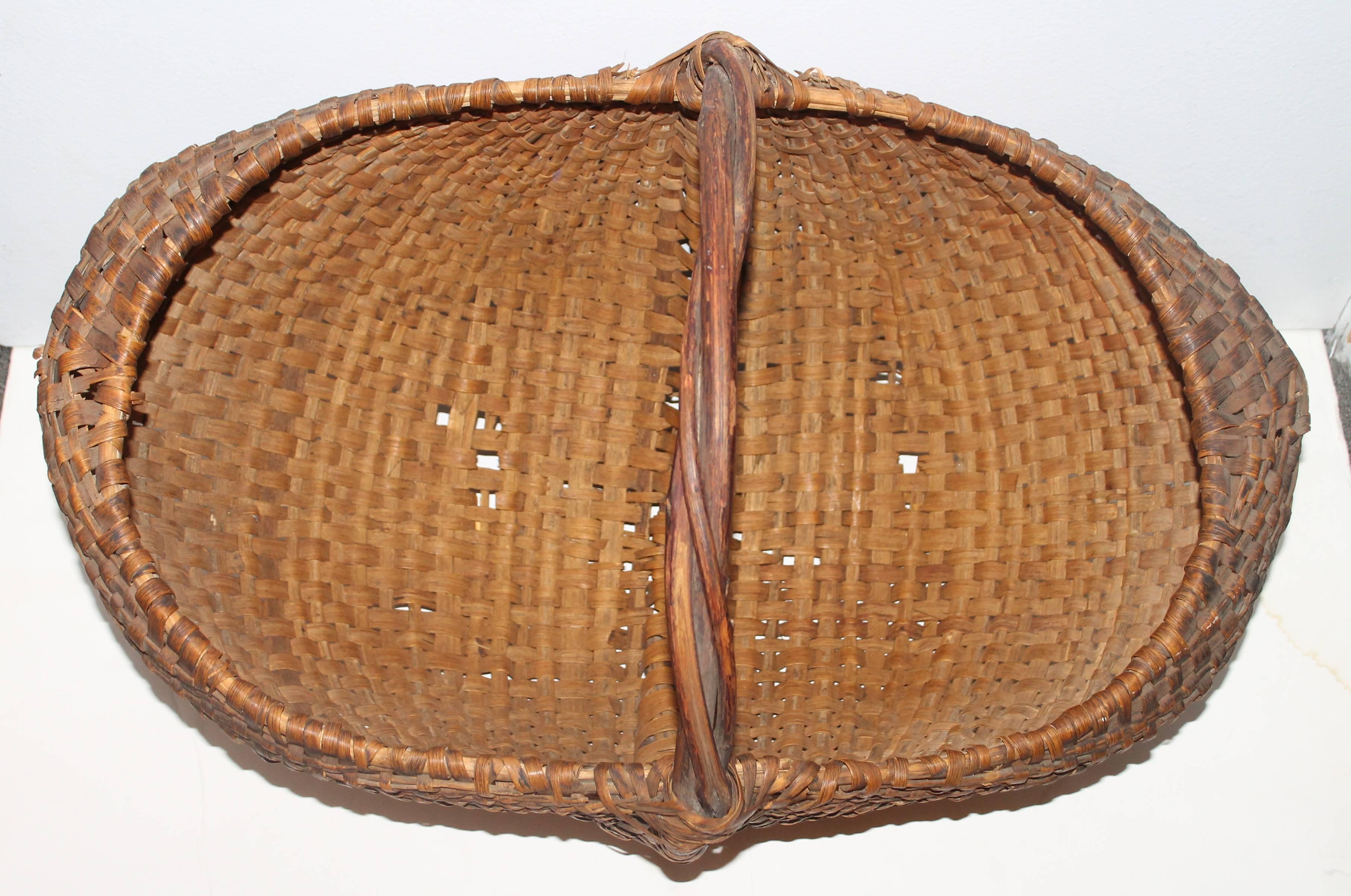 This very large all original basket is in fine as found condition with very minor breaks on the bottom. The handle is like a group of grapevines or twigs twisted together as one. This basket is quite unusual and a great addition to any basket or