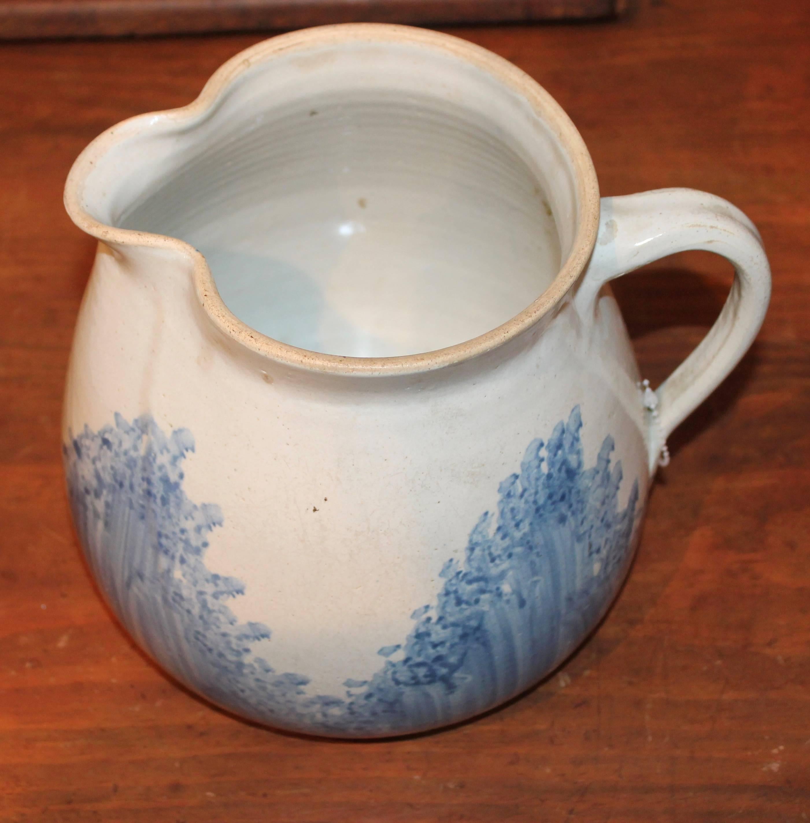 This 19th century pottery pitcher has a sponge like or spatter blue feather pattern in a salt glaze surface. The condition is very good.