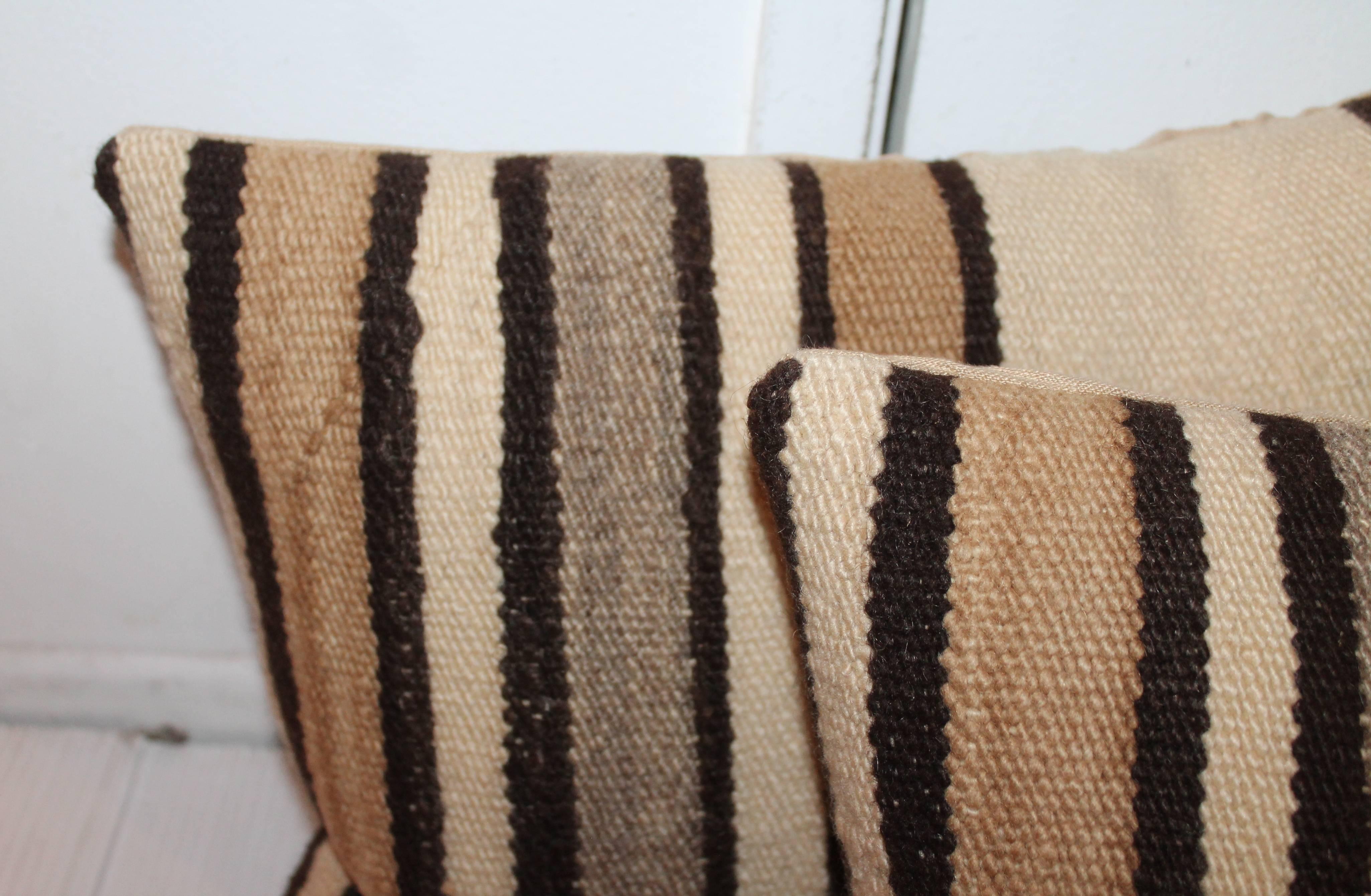 These wonderful and early stripped saddle blanket weaving pillows are sold in pairs and have tan cotton linen backings. Two pairs in stock. Sold in pairs.