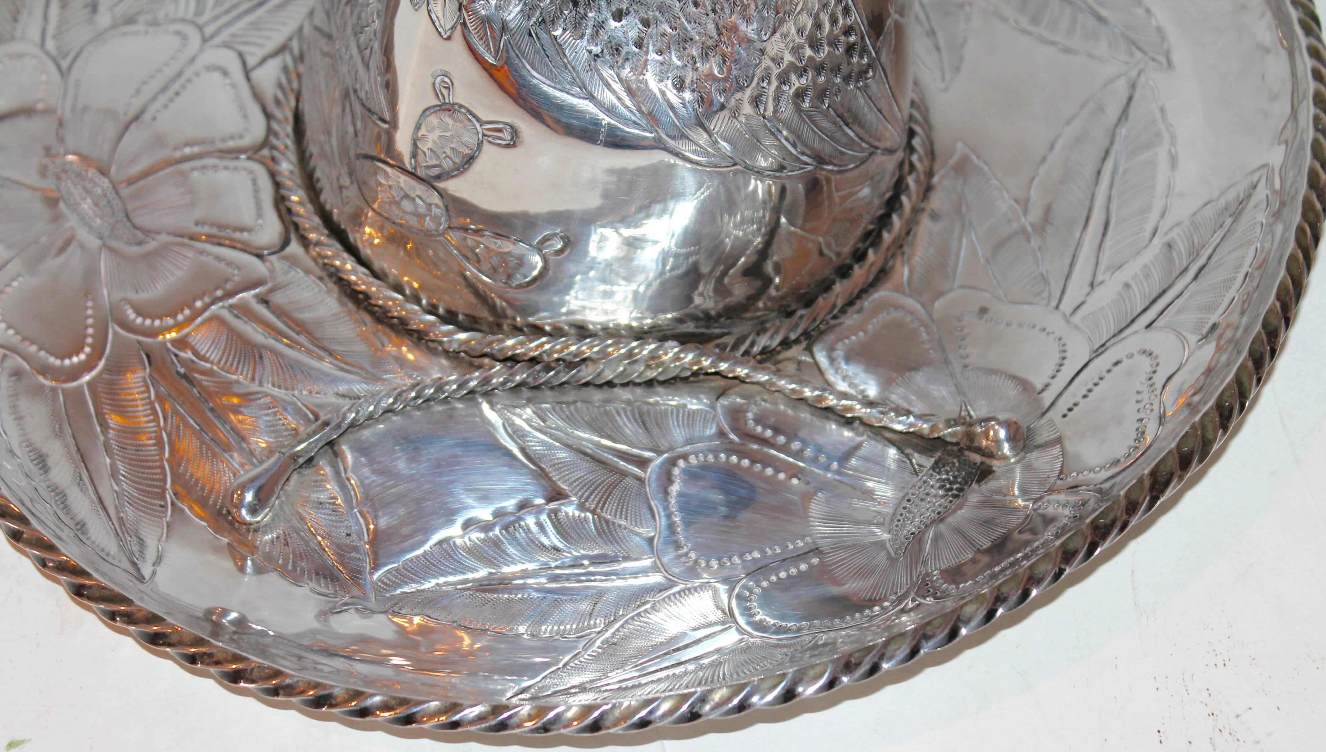 This extra large sterling silver sombrero is stamped Taxco Mexico and sterling 925. This very heavy sterling silver hat has a eagle engraved with a snake in its mouth and roped border. The floral engraved back round is typical of the Mexican motif.
