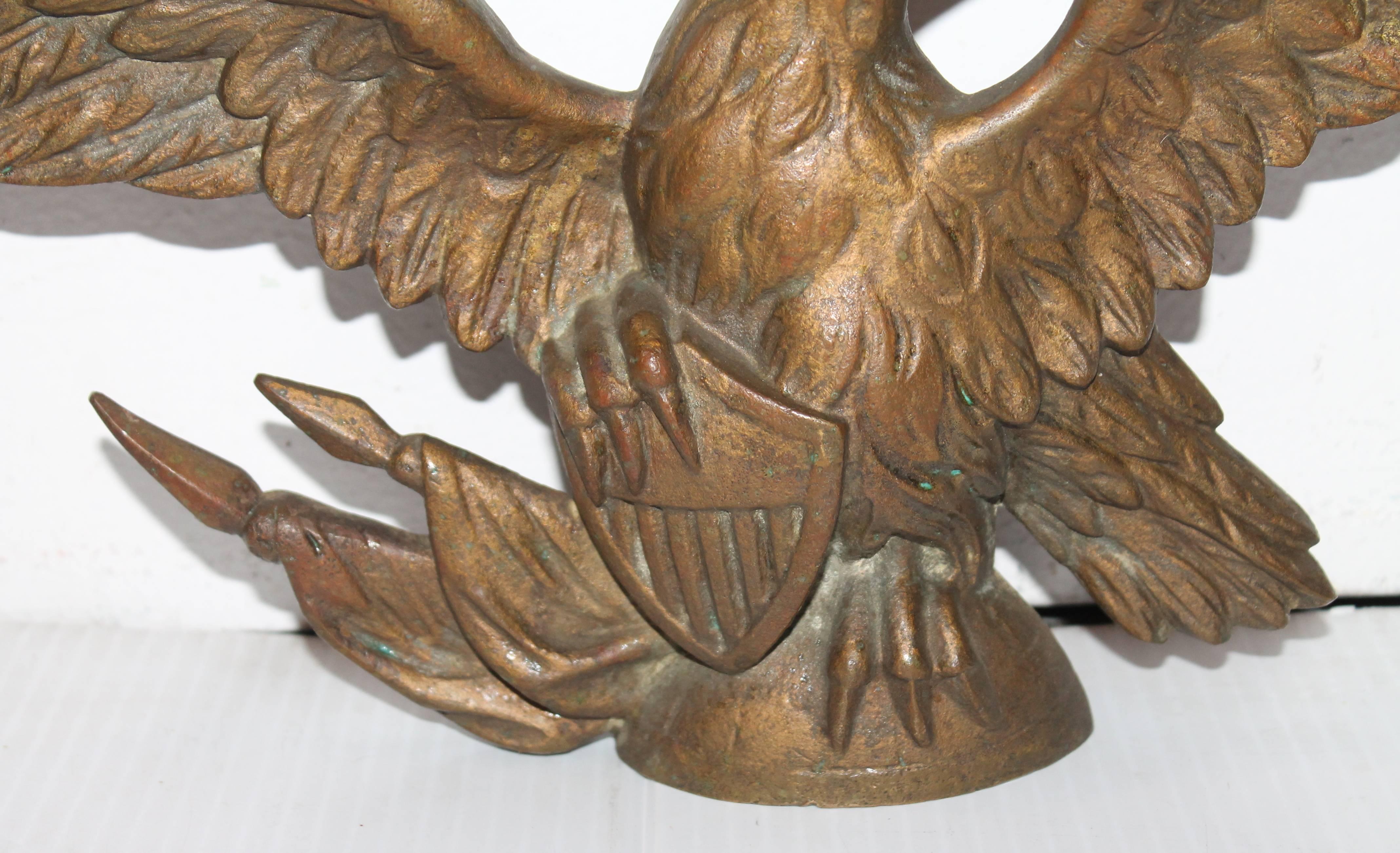 This wonderful solid bronze eagle is flanked on a shield and two cross flags. With the wing span it is 15" inches wide. Great topper for a mantel or shelf. The eagle also has fragments of gilded surface.