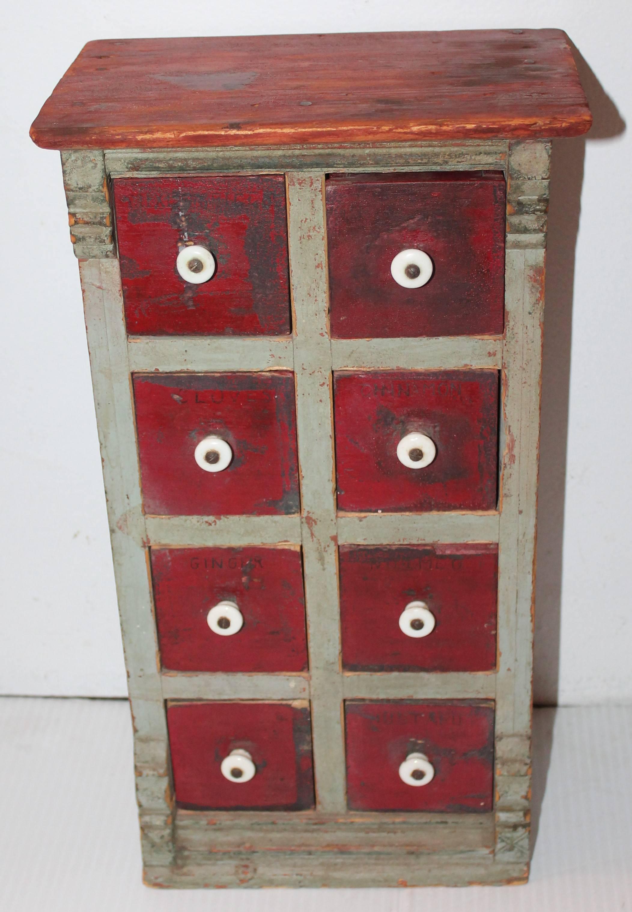 This amazing all original painted New England table top spice cabinet in red and grey is in great untouched surface. This eight-drawer cabinet is handmade and has spices painted on drawers. The condition is very good.