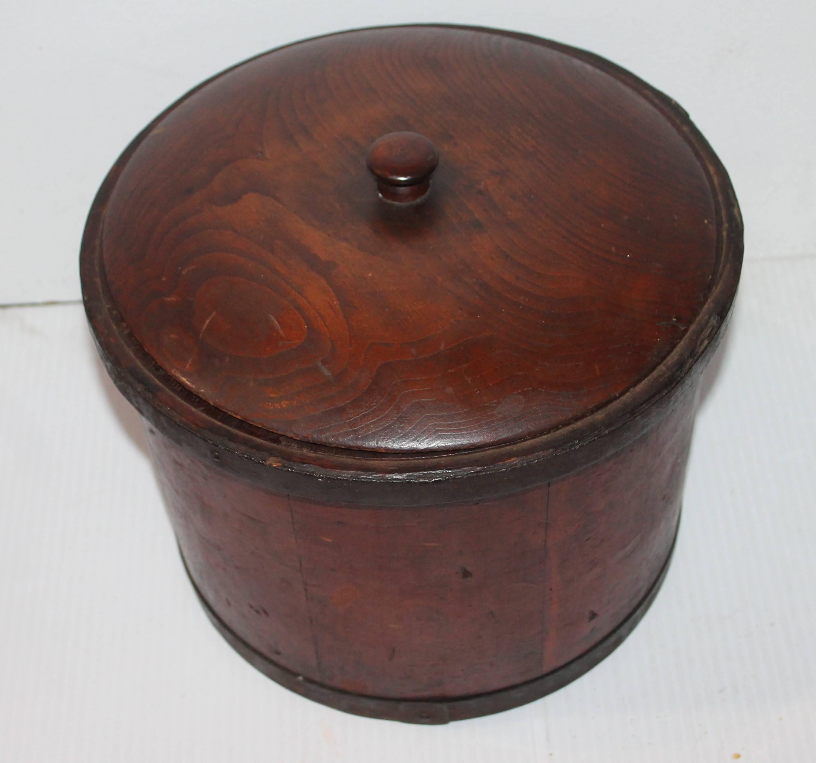 This fantastic original red painted storage box is made in the form of a old New England measure with a make do lid. The painted surface is undisturbed. The box has metal bands around. The condition is fantastic.