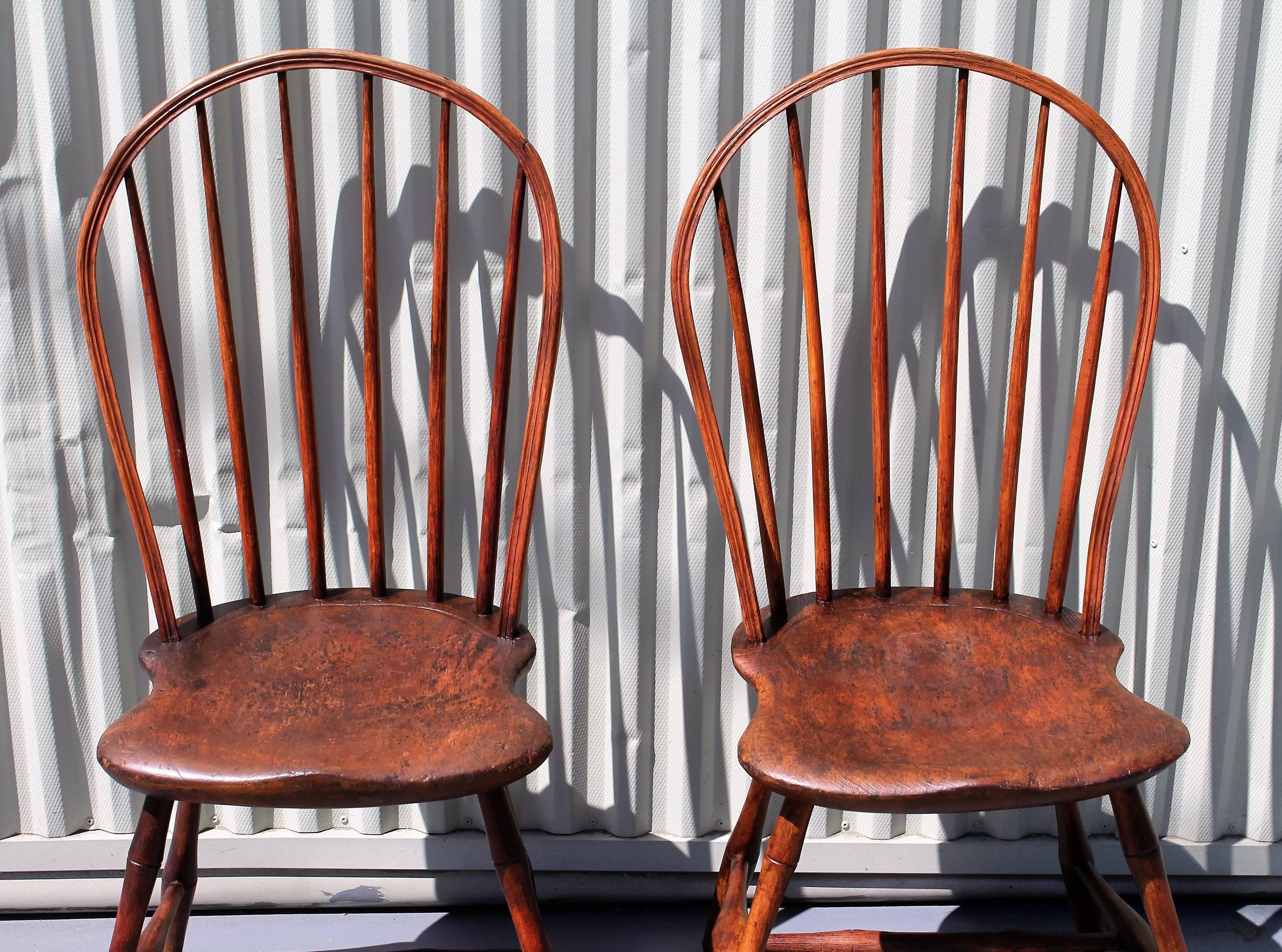 These amazing early windsor chairs are in fine, sturdy condition. The surface is old and worn with a over finish and the wear is consistent with age and use. The saddle seats make the chairs super comfortable. Sold as a pair only.
