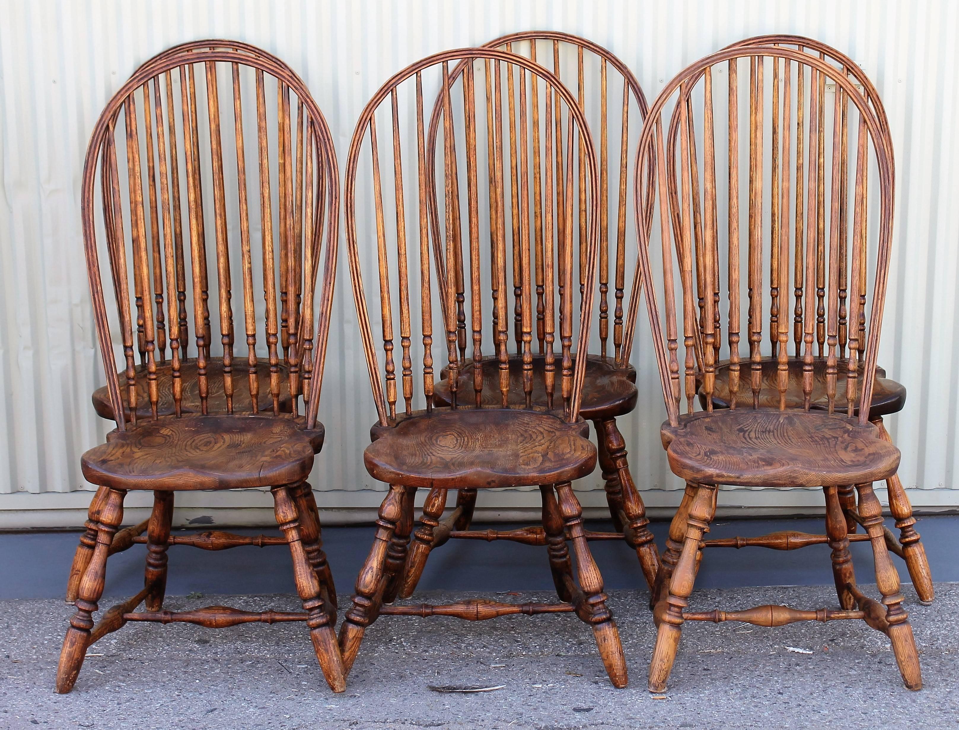 These chairs are from the early 20th century and are fine handcrafted hoop back Windsor chairs. They are made of hickory and oak and are all mortised and pegged. The spindles are mortised through as well as the legs through the saddle seats. These