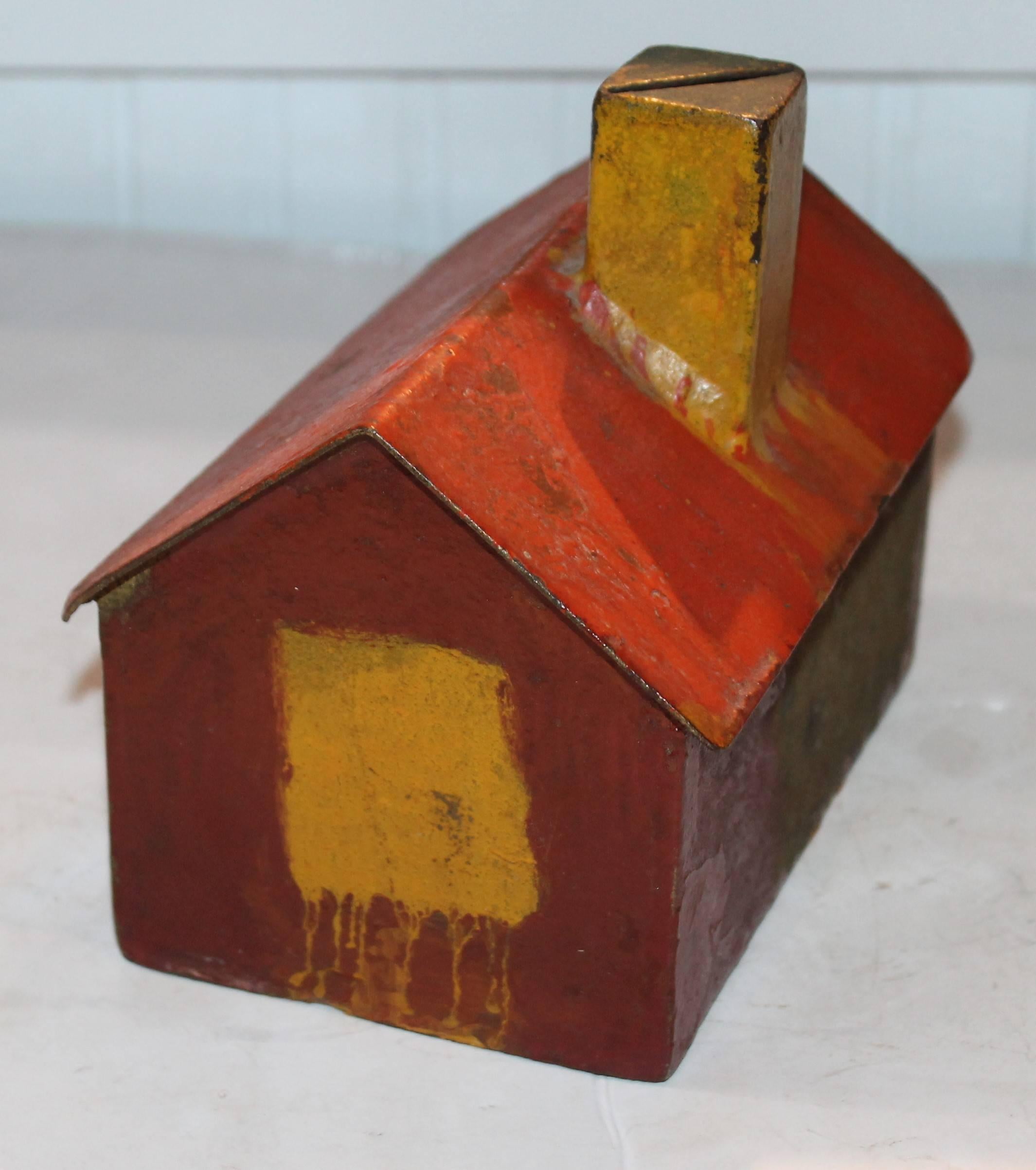 This fun 19th century Folk Art bank is made from sheet iron and all original salmon and mustard paint. It is funny there is no way to get the money out once it goes in. You would have to break the house open. Condition is good.