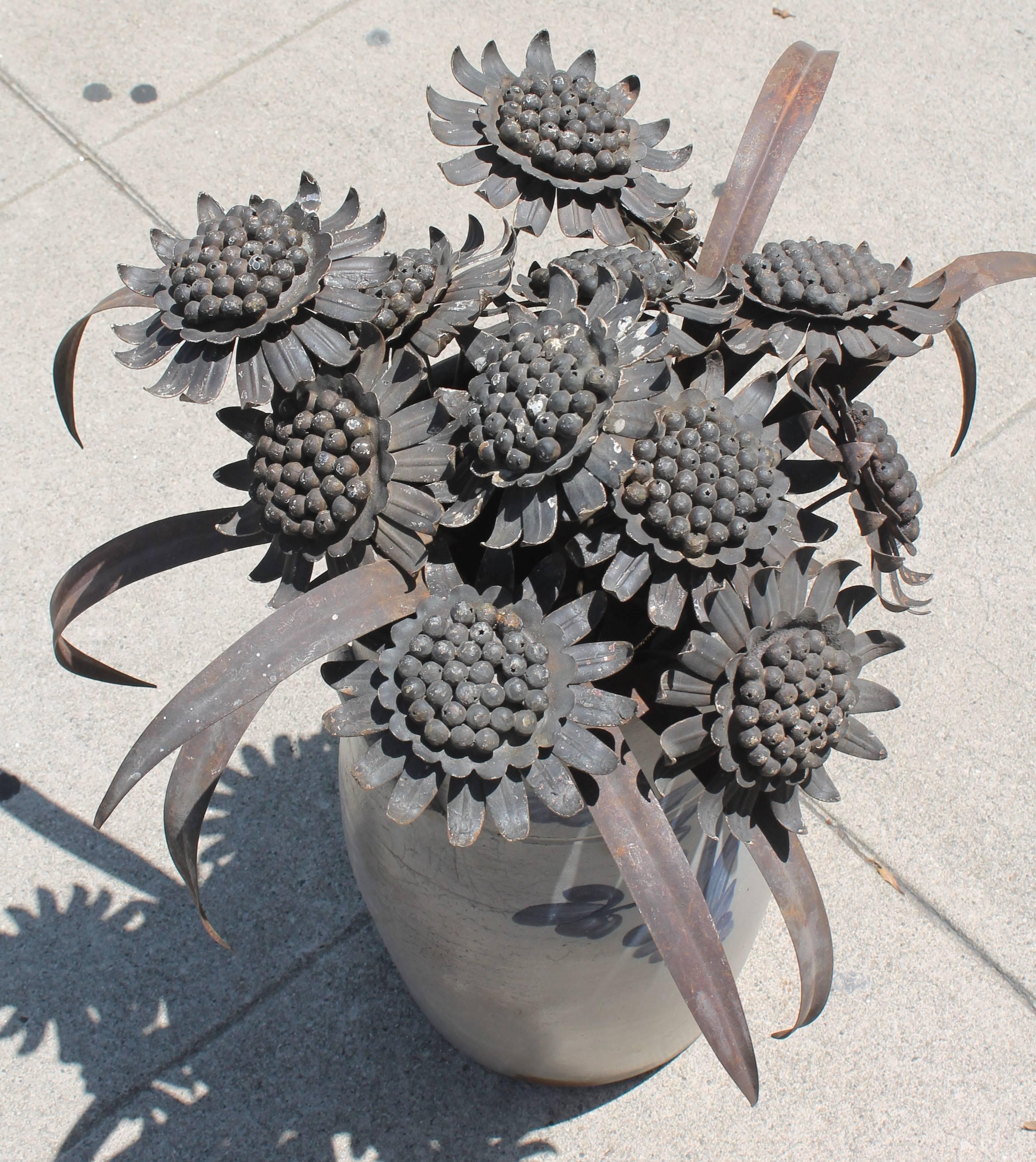 1910-1925 original paint and great patinated with a slight coat of black and silver paint, worn tin and iron collection of sunflowers. The stems have been welded onto the sunflower bottoms. There are 12 sunflowers and 9 leaves to go with this