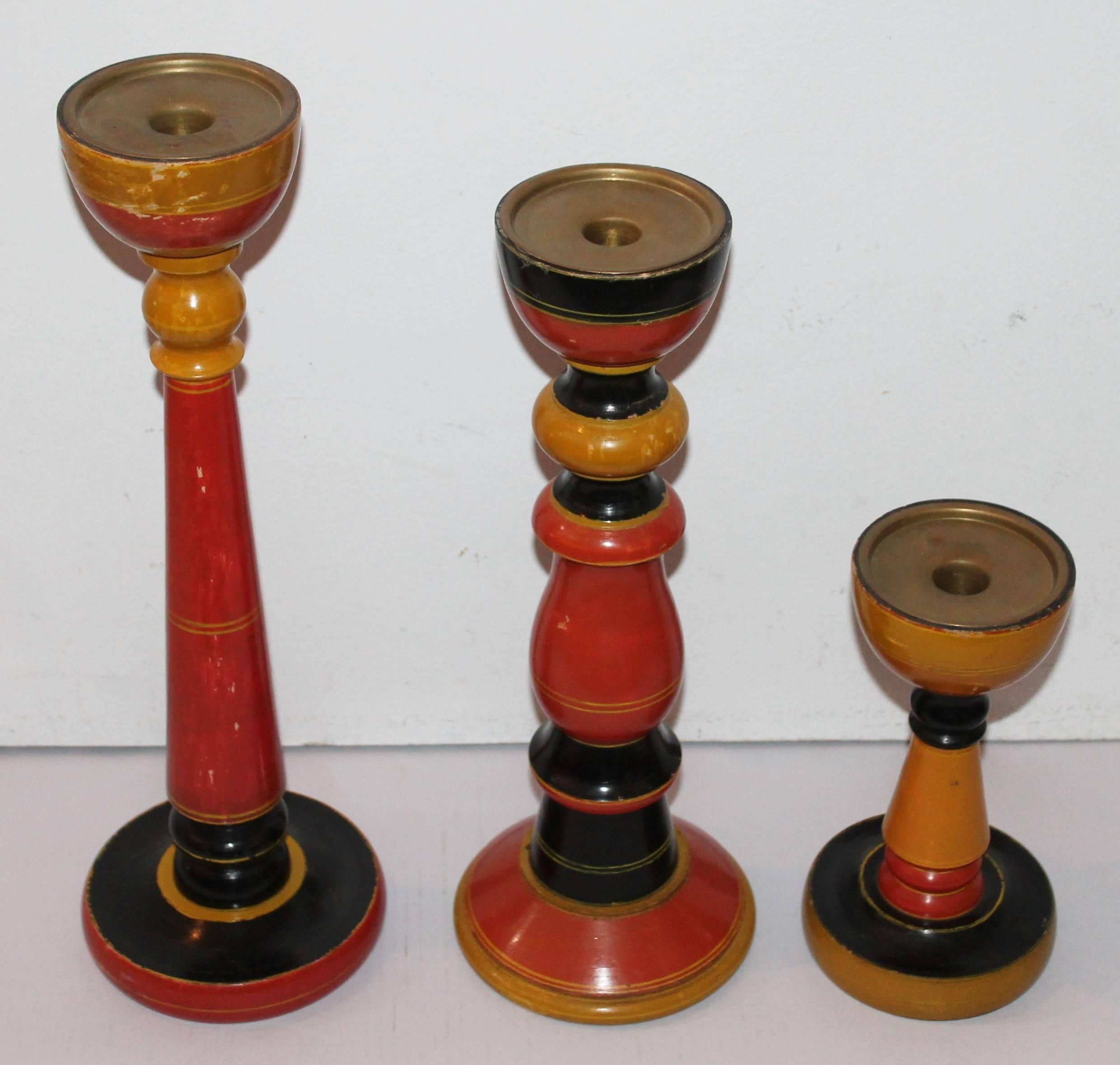 This collection of three southwestern original painted wood candle stick holders. The condition is very good. Sold as a set of three. The insert skirt is brass. Measures: The first is 9" high x 4.5" wide. Second is 15" x 5.5".