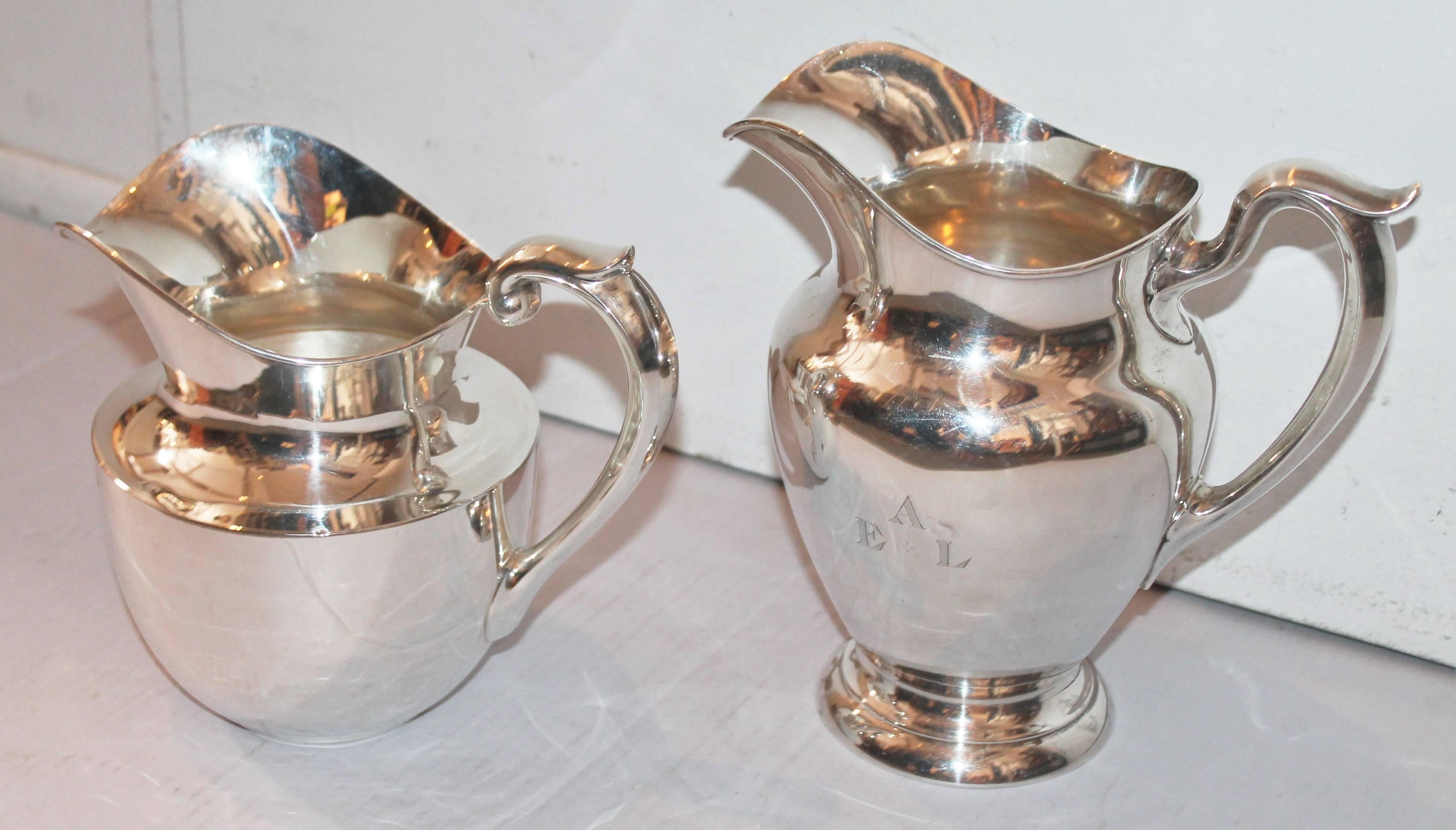 The wide shorter pitcher is marked sterling and is 7.5 inches tall x 8.5 wide and in pristine condition. The second pitcher is very heavy and is signed Gorham Sterling 4 1/4 pint. It is 9" high x 9 1/4 wide. The condition is pristine. Sold as a