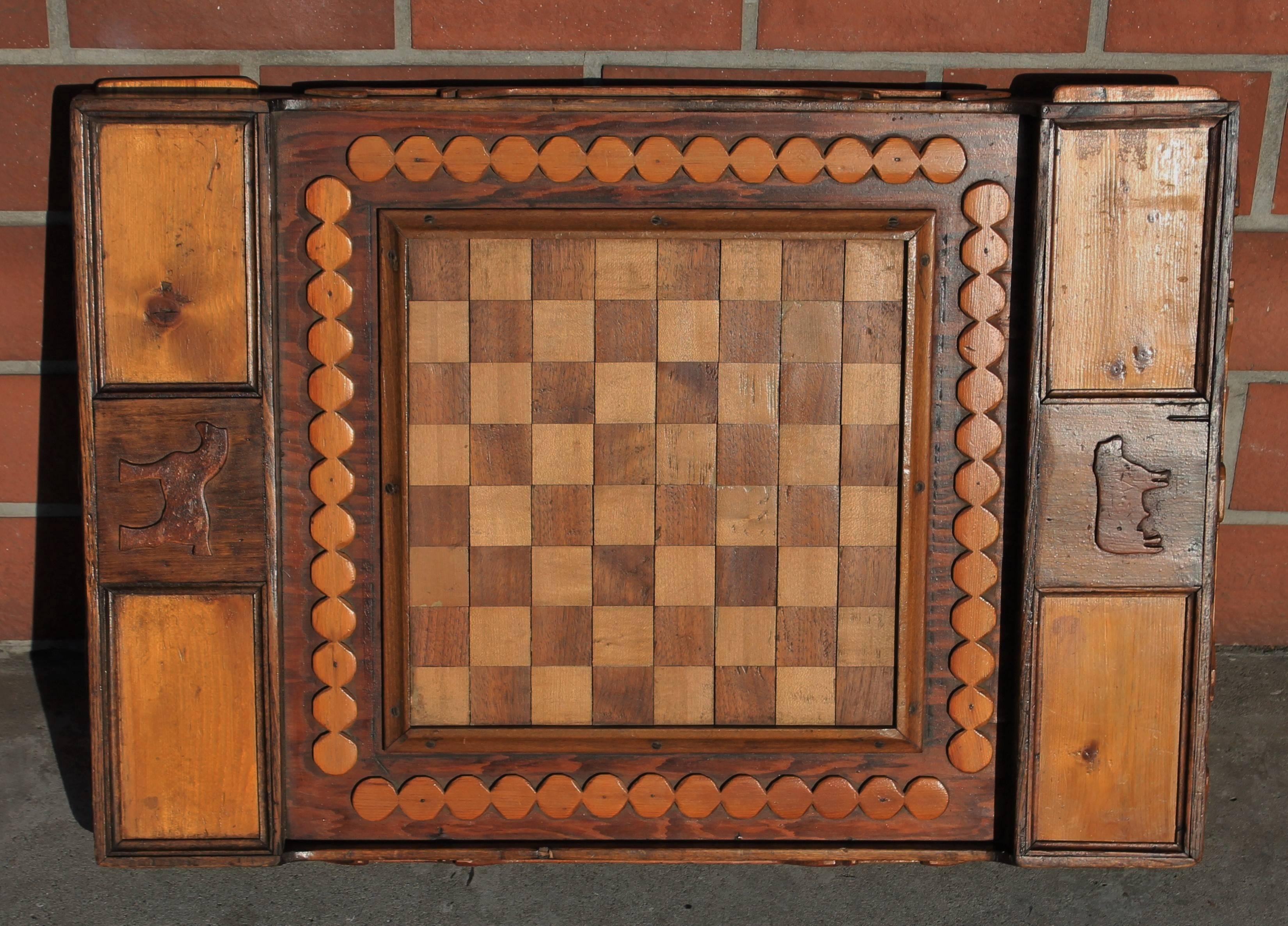 This amazing inlaid early 20th century game board is a reversible and contains the original wood checkers with in the hidden drawers. This handmade board also has hearts and arrows on the outside picture frame molding. The condition is very good.