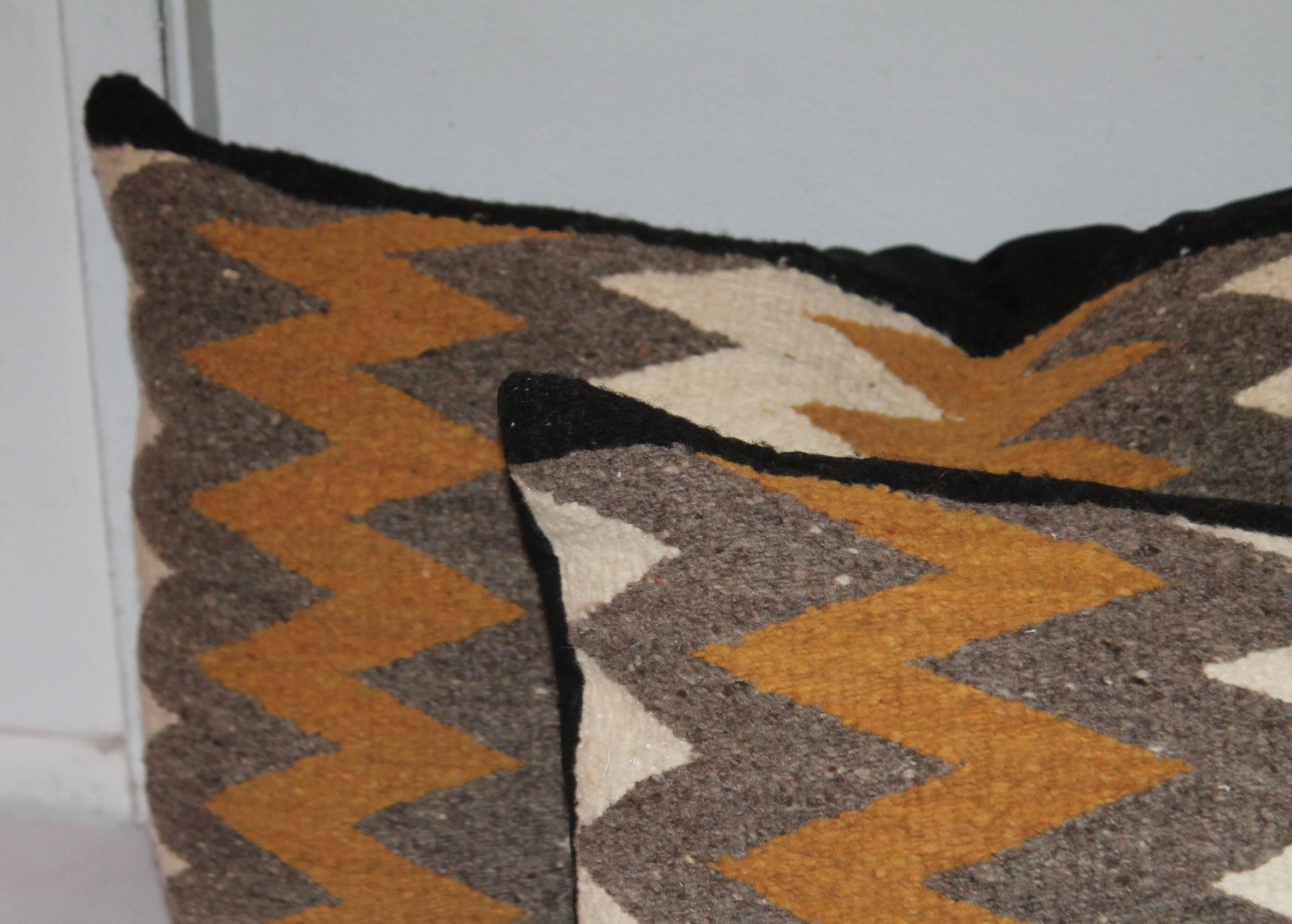 Cette paire de coussins de couverture de selle Navajo est en bon état et a un dos en lin de coton noir.