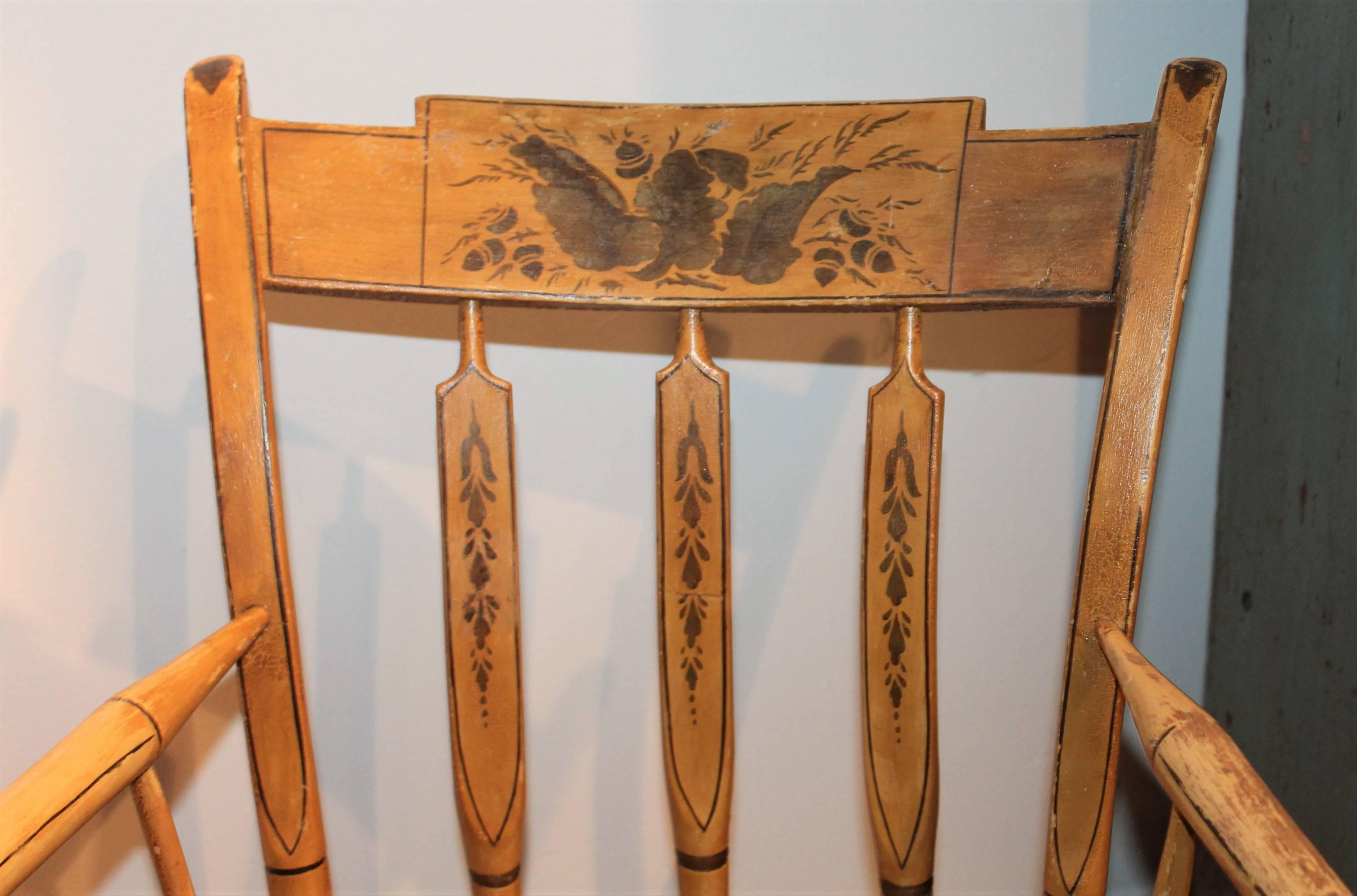 This wonderful 19th century original paint decorated windsor rocking chair is in great condition. The stencil is gilded paint on a mustard painted ground. This rocking chair was found in Maine.