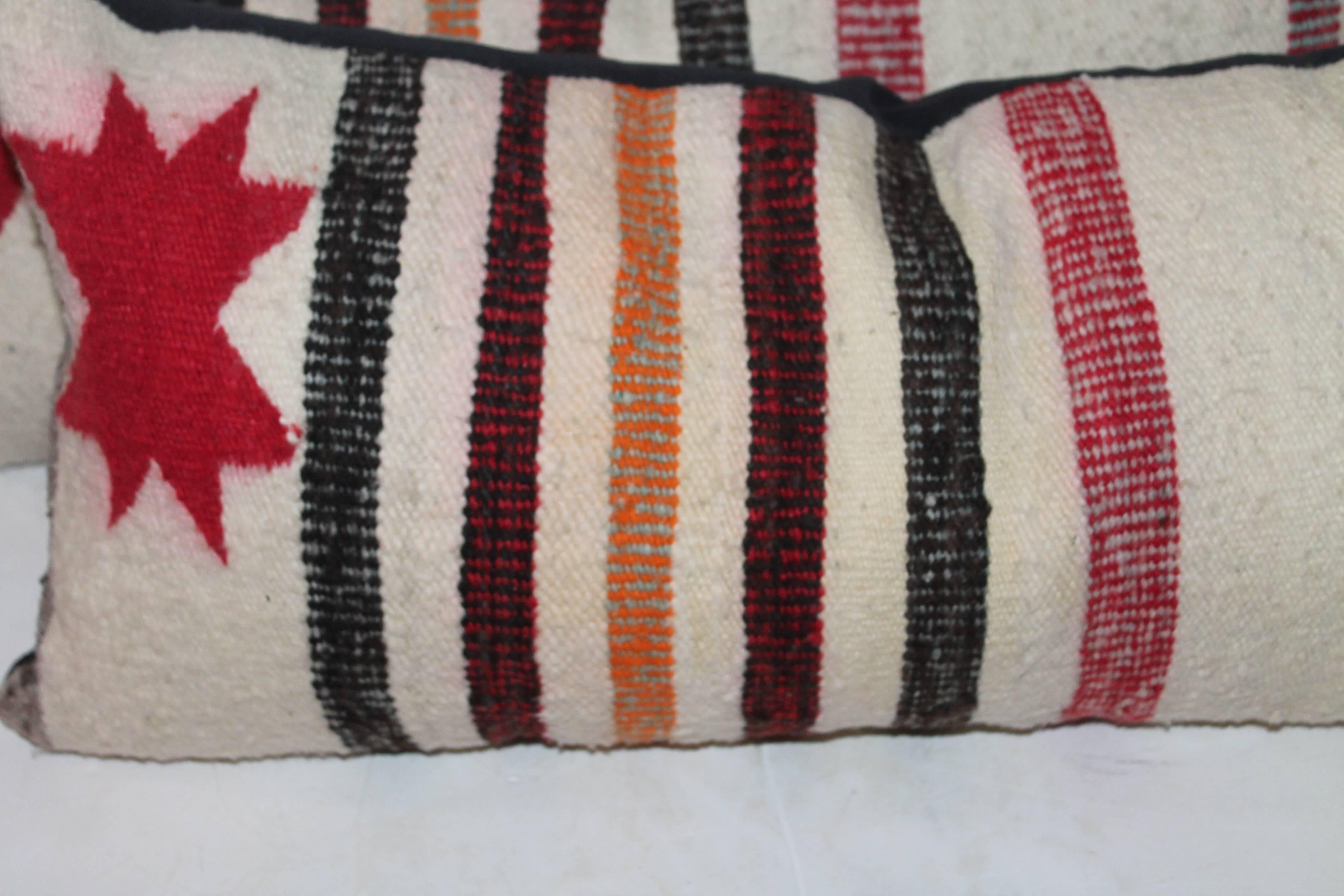 These saddle blanket weaving's have red stars pattern in the end corner of each pillow. There are two pairs in inventory. The backing is in a black cotton linen. Condition is very good. Sold in pairs.