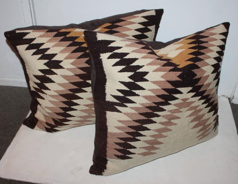 These large Navajo weaving bolster pillows are in a eye dazzler pattern and have a black cotton linen backing. Sold as a matching pair.