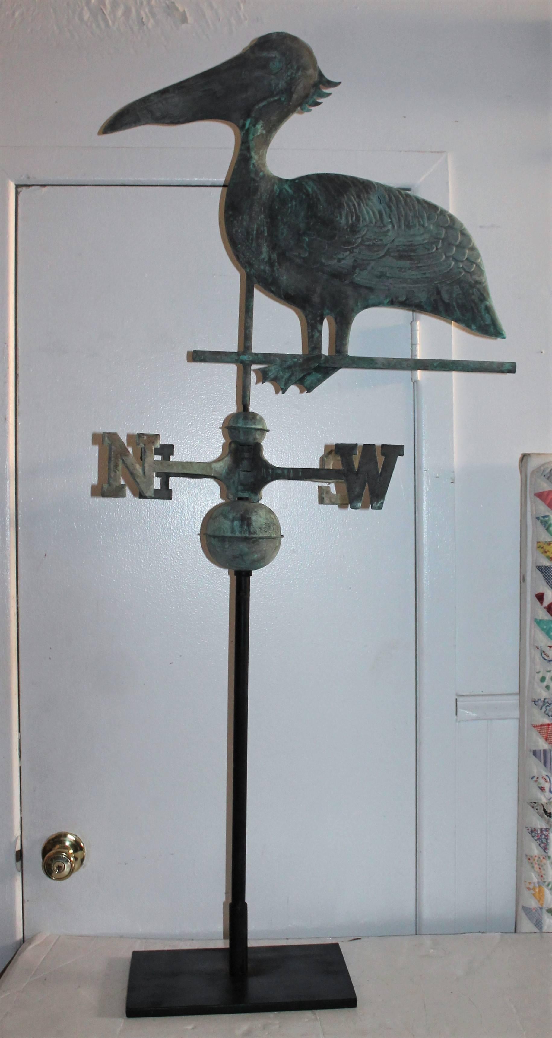 This fun crazy shore bird has a wonderful aged surface and its original patinated directionals. This great weather vane has the original iron rod of which could be mounted on a roof top or kept on the custom iron base. This is included. Condition is
