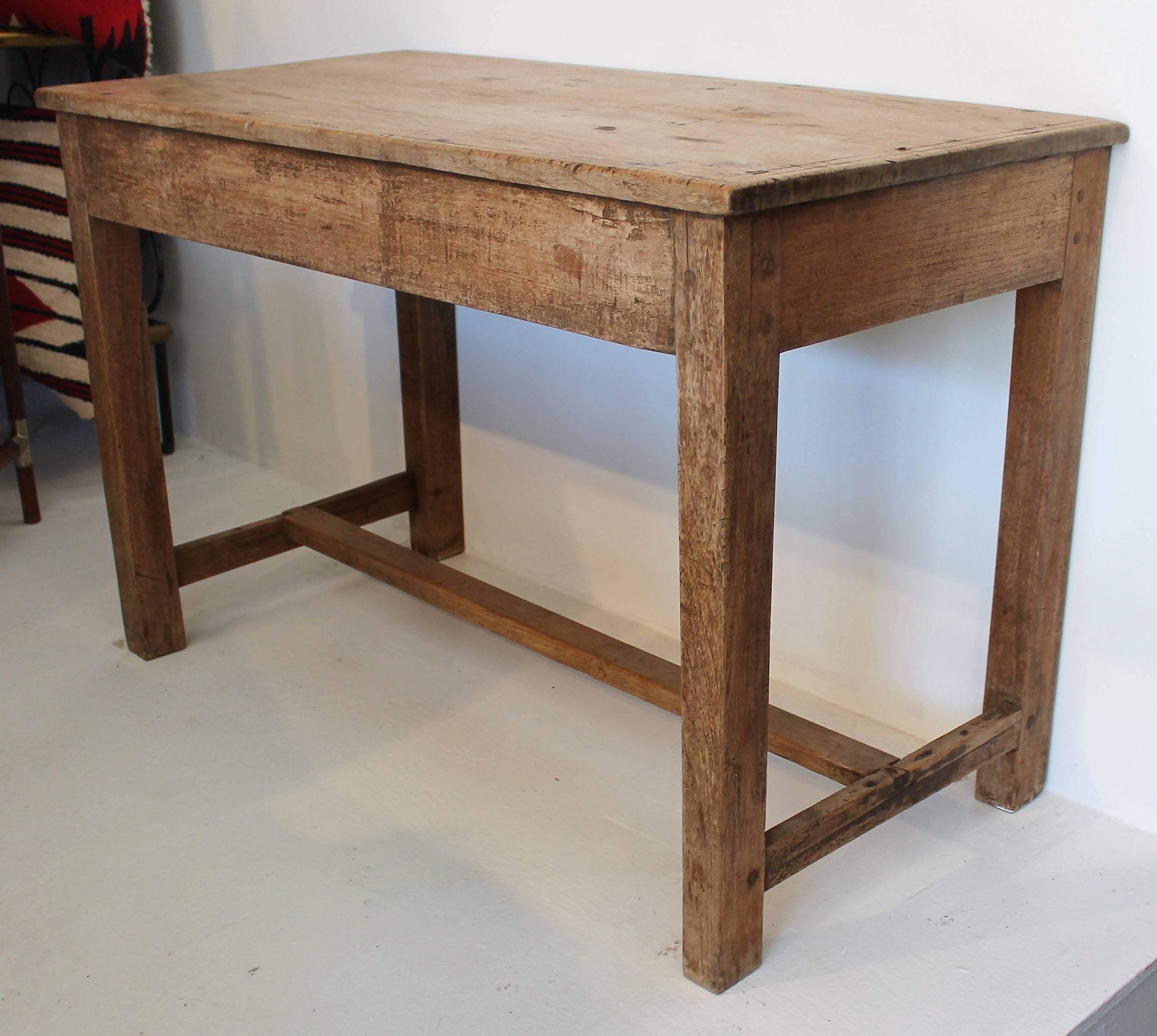 This early and rustic walnut side table is in good condition and very sturdy. The construction is wood pegs and early cut handmade nails. The centre stretcher is dovetailed in. This is a very early handmade table.