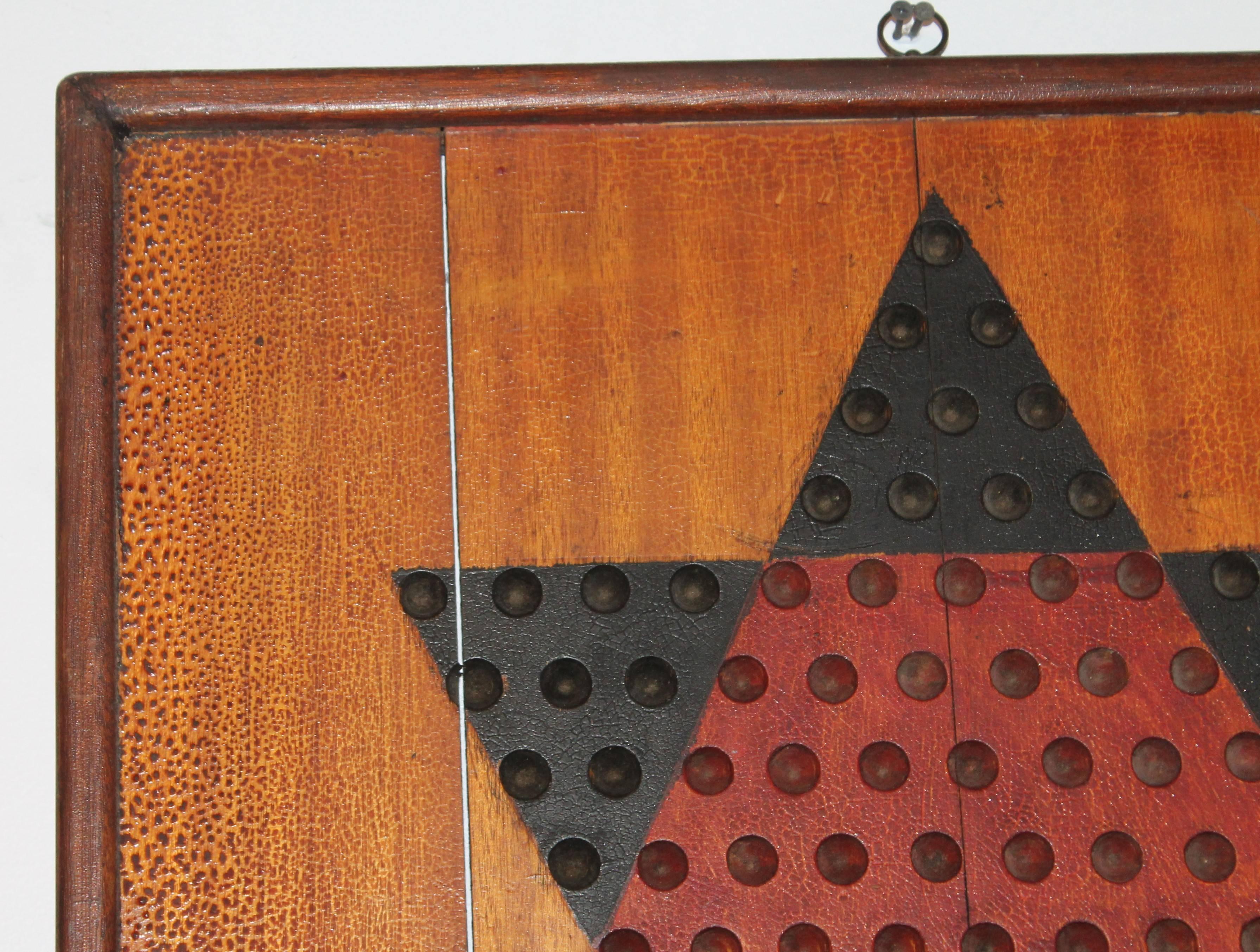 This double-sided original painted monumental Chinese checkers and checker board in one has a spectacular grungy undisturbed surface. This thick board has the original brass hanger on top. The condition is very good. This is a one of a kind handmade