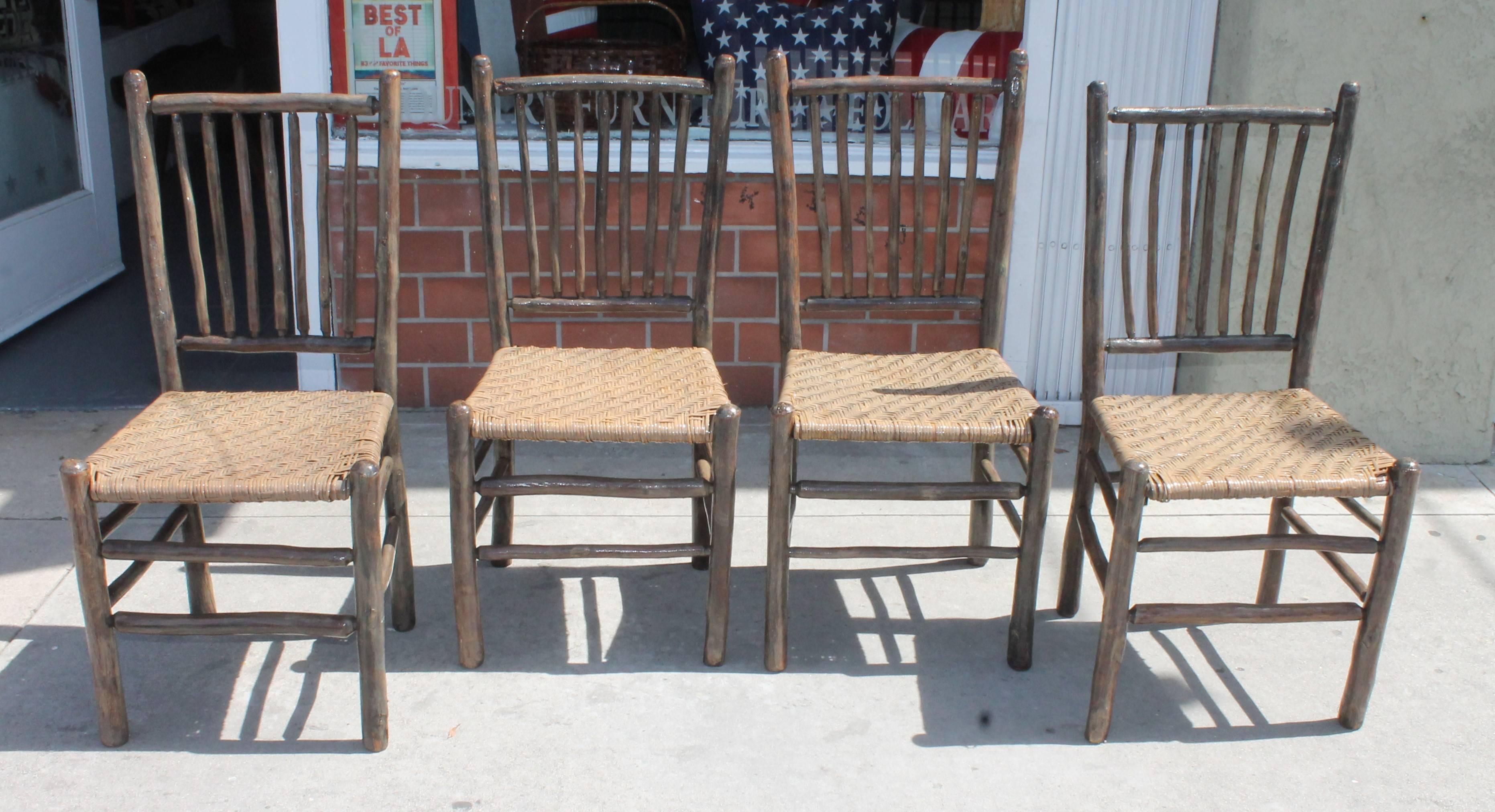 Amazing set of four matching original grey painted rustic hickory dining chairs .The seats are the original woven seats and the chairs are signed on the reverse Old Hickory Furniture Company, Martinsville ,Indiana stamped on the lower back legs. The