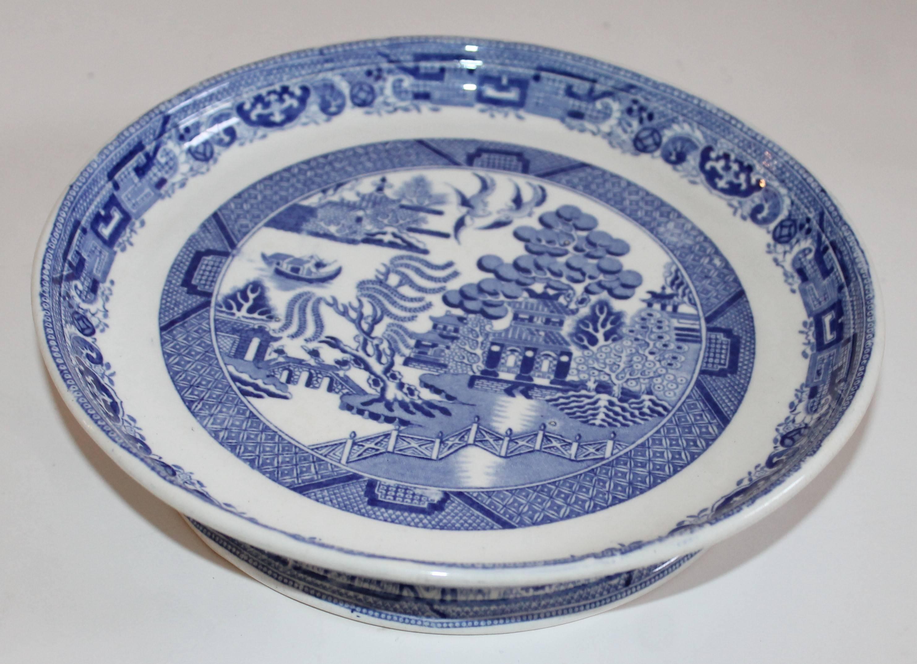 19th century blue willow cake platter. This great blue willow cake platter is in amazing condition. The stand is white and features the classic Blue Willow pattern. The pedestal of the stand also features blue detailing around the base.