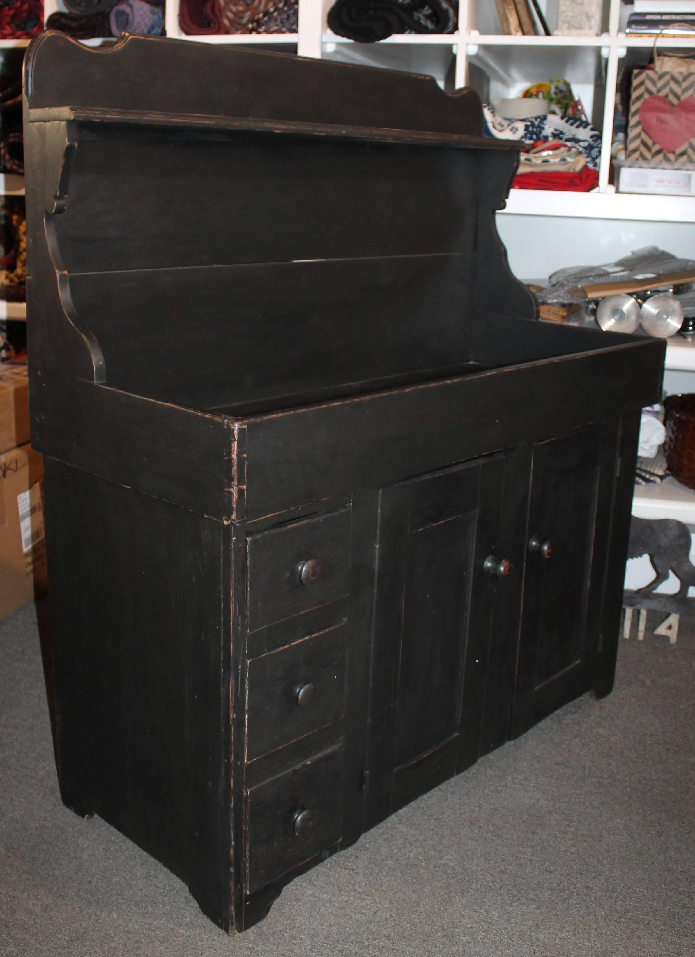 This fine form dovetailed case and drawers dry sink hutch is in wonderful as found condition. The black painted surface is secondary paint along with the cream painted interior is over paint. All hardware and door pulls are original to the piece.