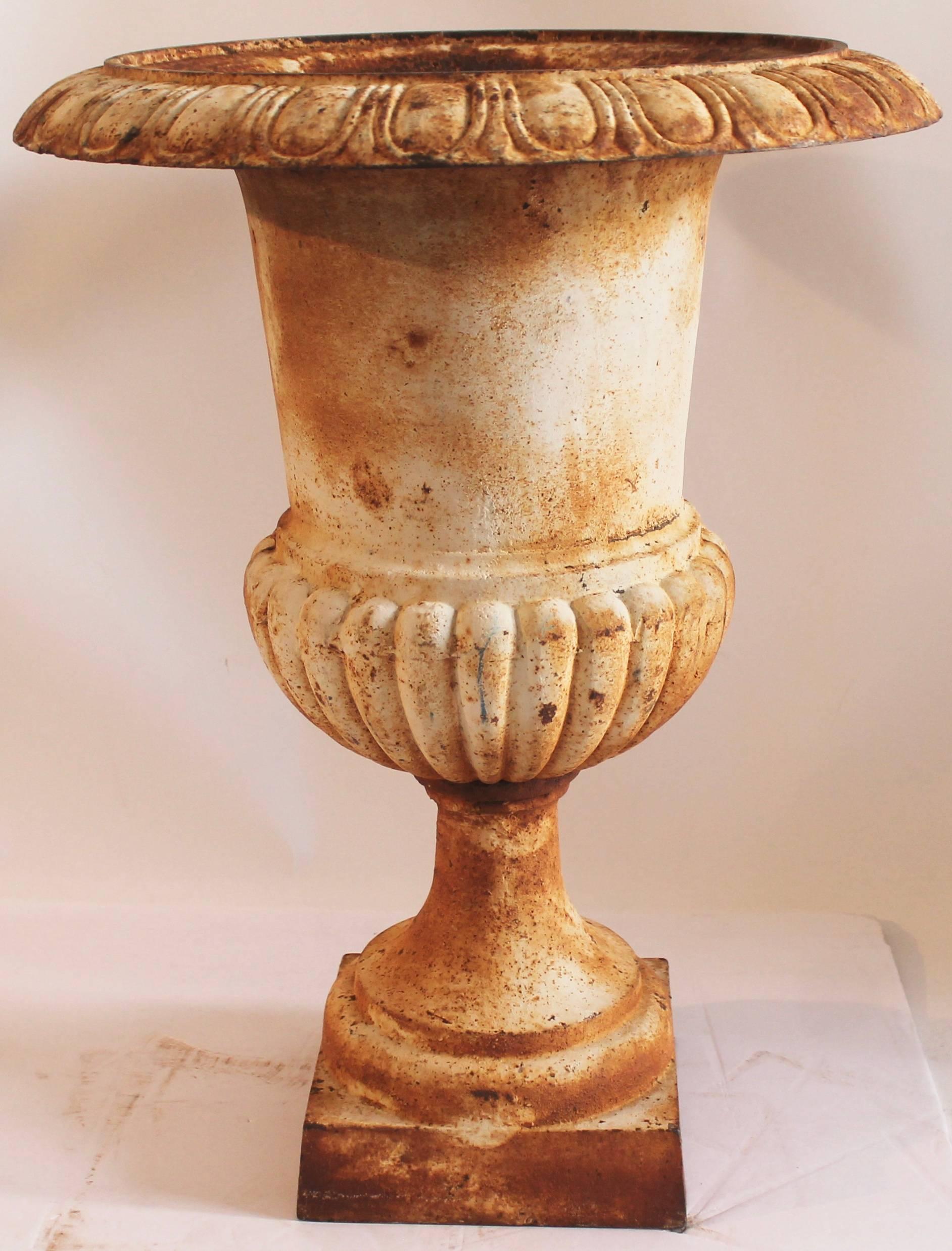 This 19th century distressed white painted monumental iron urn is in great as found condition. The fragments of white painted surface are through-out.