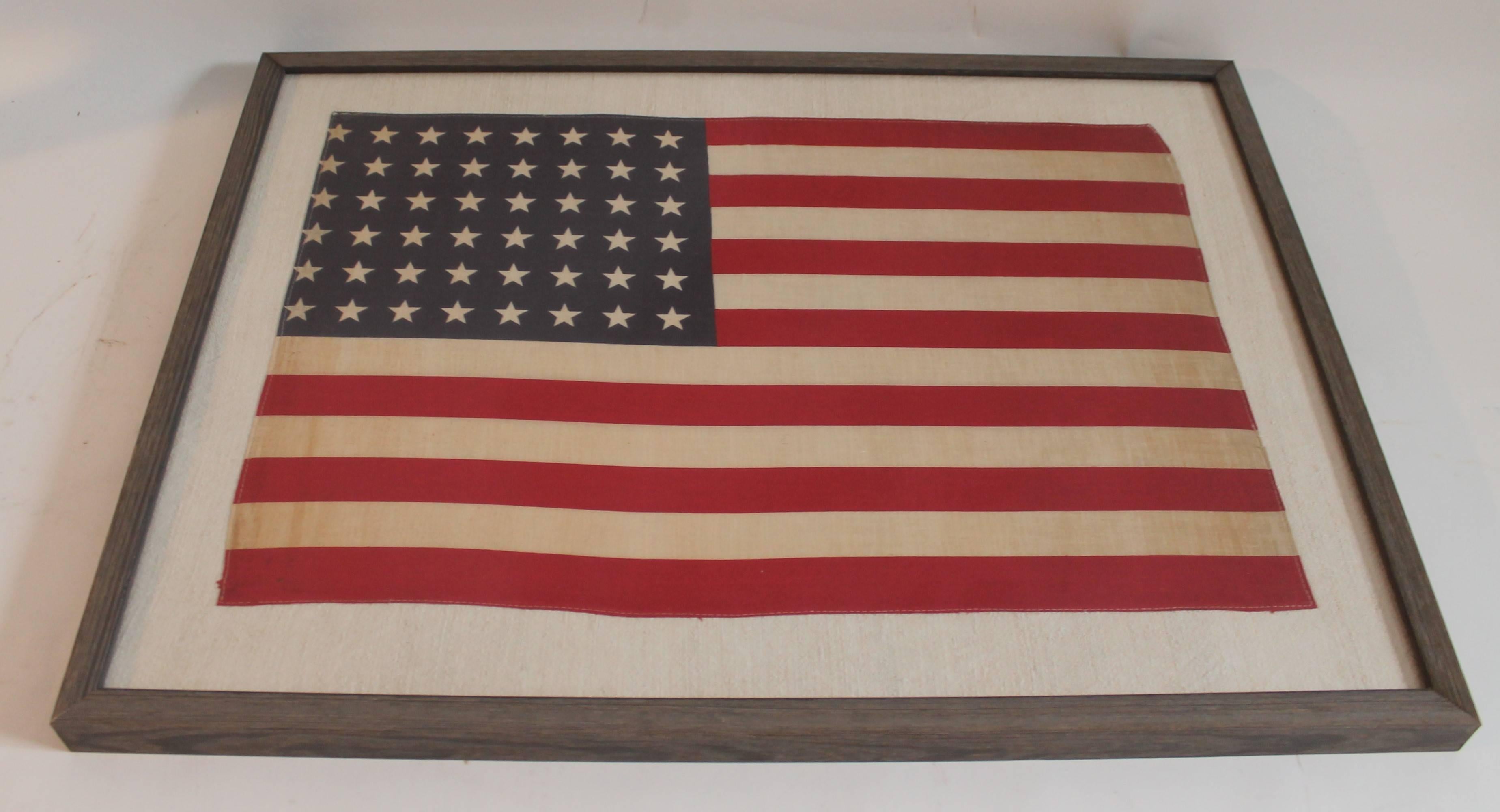 This 48 star flag is hand-sewn on cotton homespun linen and is in a country rustic wood frame. Great for in a den or bar. The condition of the flag is good with minor discoloration.