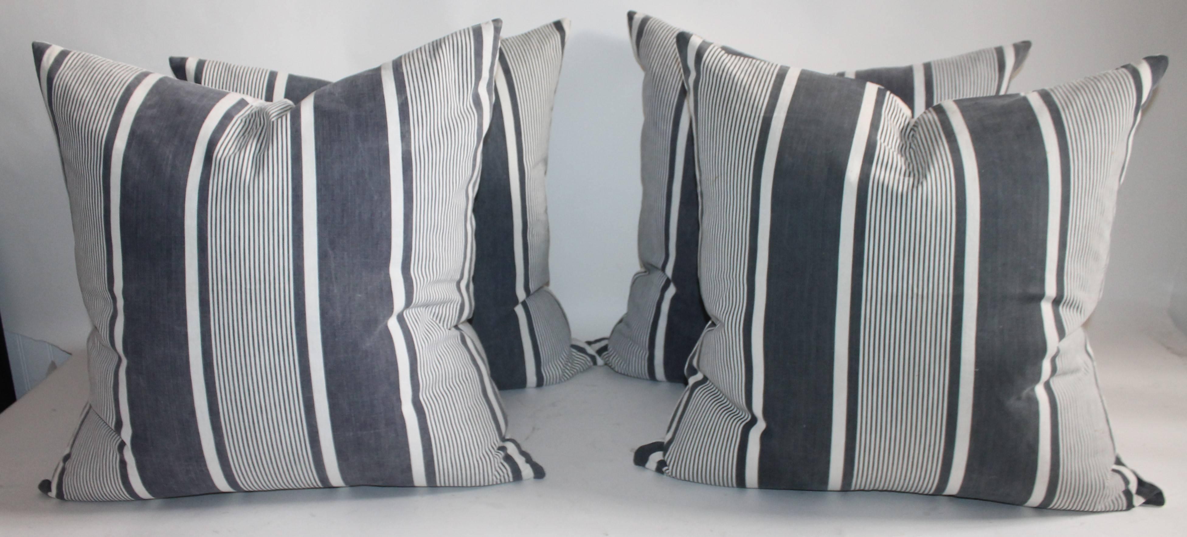 This group of four 19th century French black and white striped ticking pillows are in great as found condition. The faded black looks a little like grey in some lighting. The backing is in a white homespun linen. The inserts are down and feather