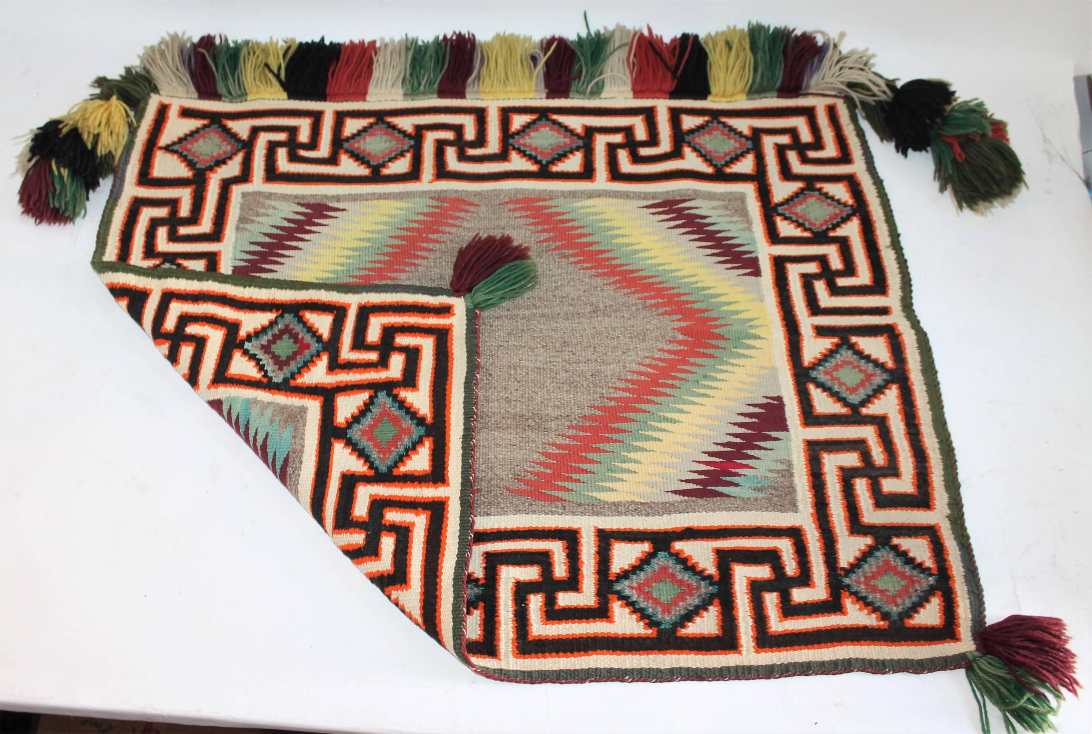 This little gem is a real find. Quite rare with a German town yarn and fringe. This Tess Nos Pos is in pristine as found condition. It is a fancy saddle blanket with all the original fringe.

Measurements are given from fringe to fringe. Height,