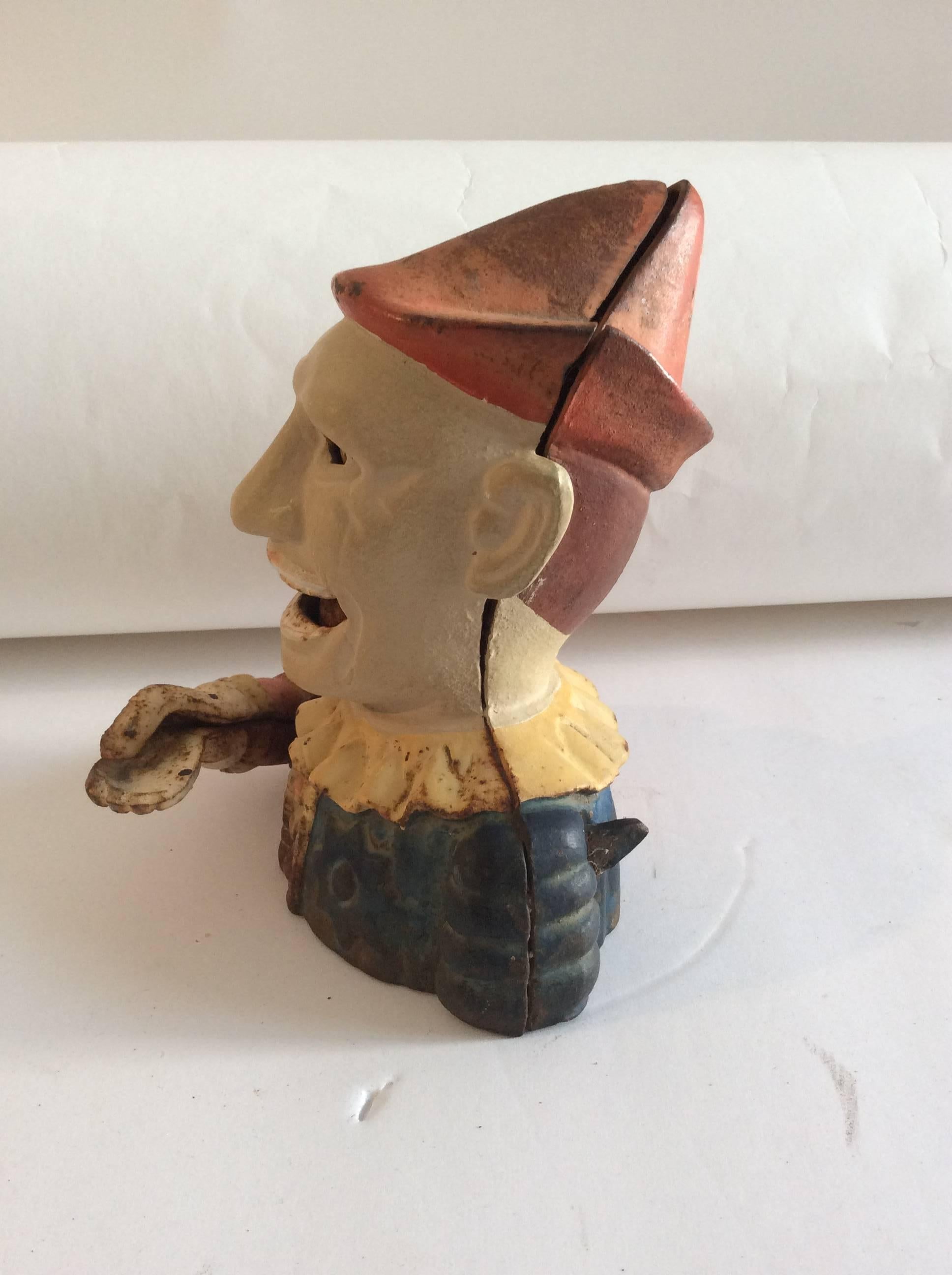 This fun and folky original painted iron penny bank has the original painted surface in working condition. Put a penny in his hand and pull the lever for him to swallow the coin. The small tin plug is missing from the base.