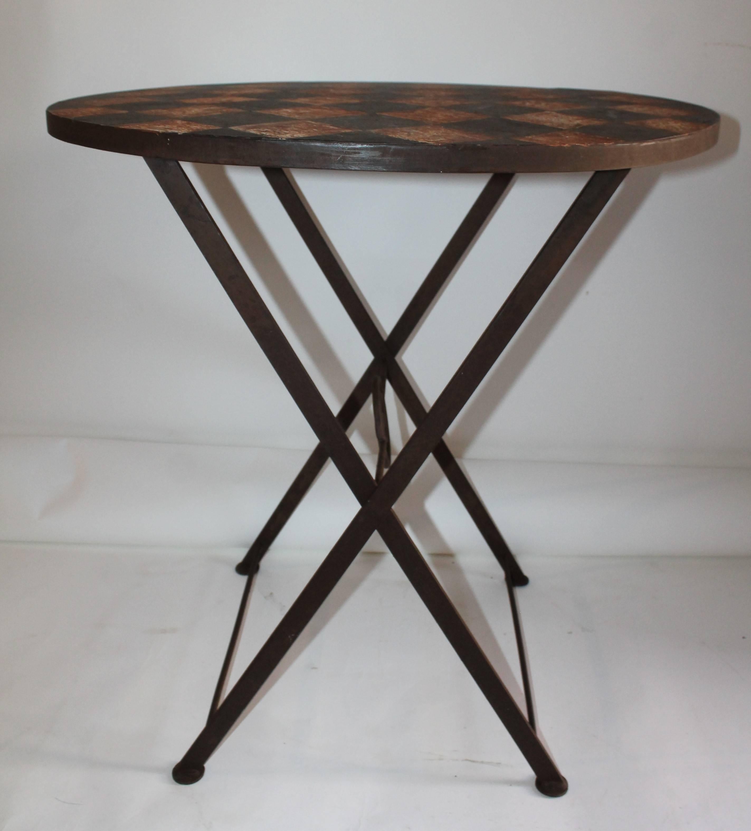 This folding painted iron garden or patio table has a checker board top and folding legs. The original painted top looks like a game board and has a wonderful patina.