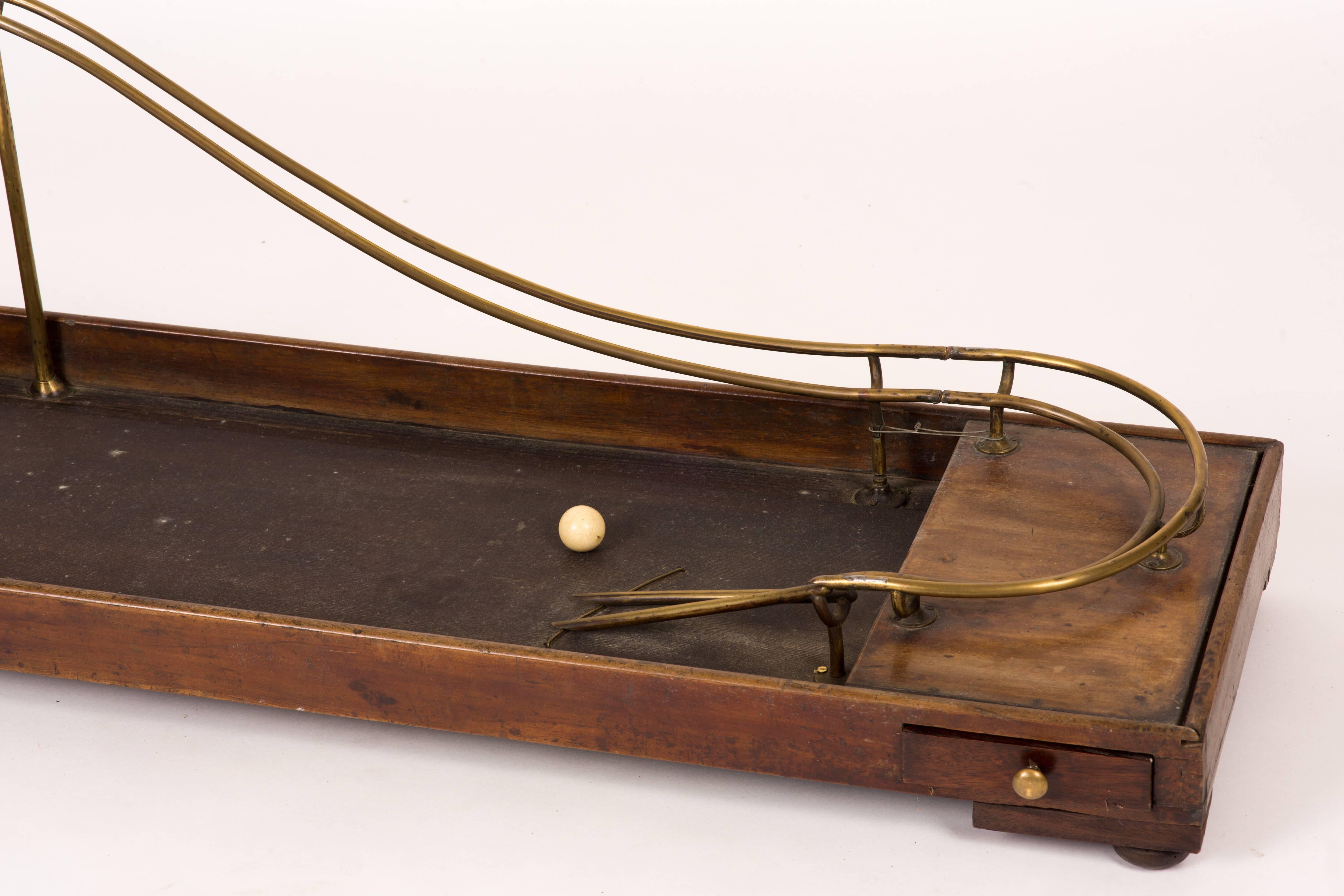 A 19th century wood and brass skittle game with separate ball and wood pins.