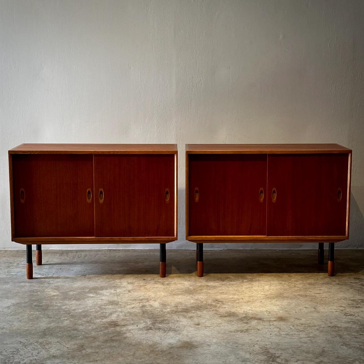 Pair of Swedish mid-century sideboards by Westberg's Möbler, crafted in teak with contrasting oak trim. Each stands on black metal feet capped with teak, combining robust utility with sleek, minimalist design. The interiors are thoughtfully