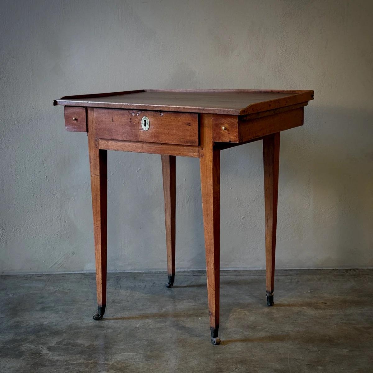Table d'appoint ou bureau en merisier des années 1880 monté sur roulettes avec trois tiroirs, un tiroir central rectangulaire avec un trou de serrure ovale en laiton et deux tiroirs carrés plus petits flanqués de part et d'autre avec des poignées