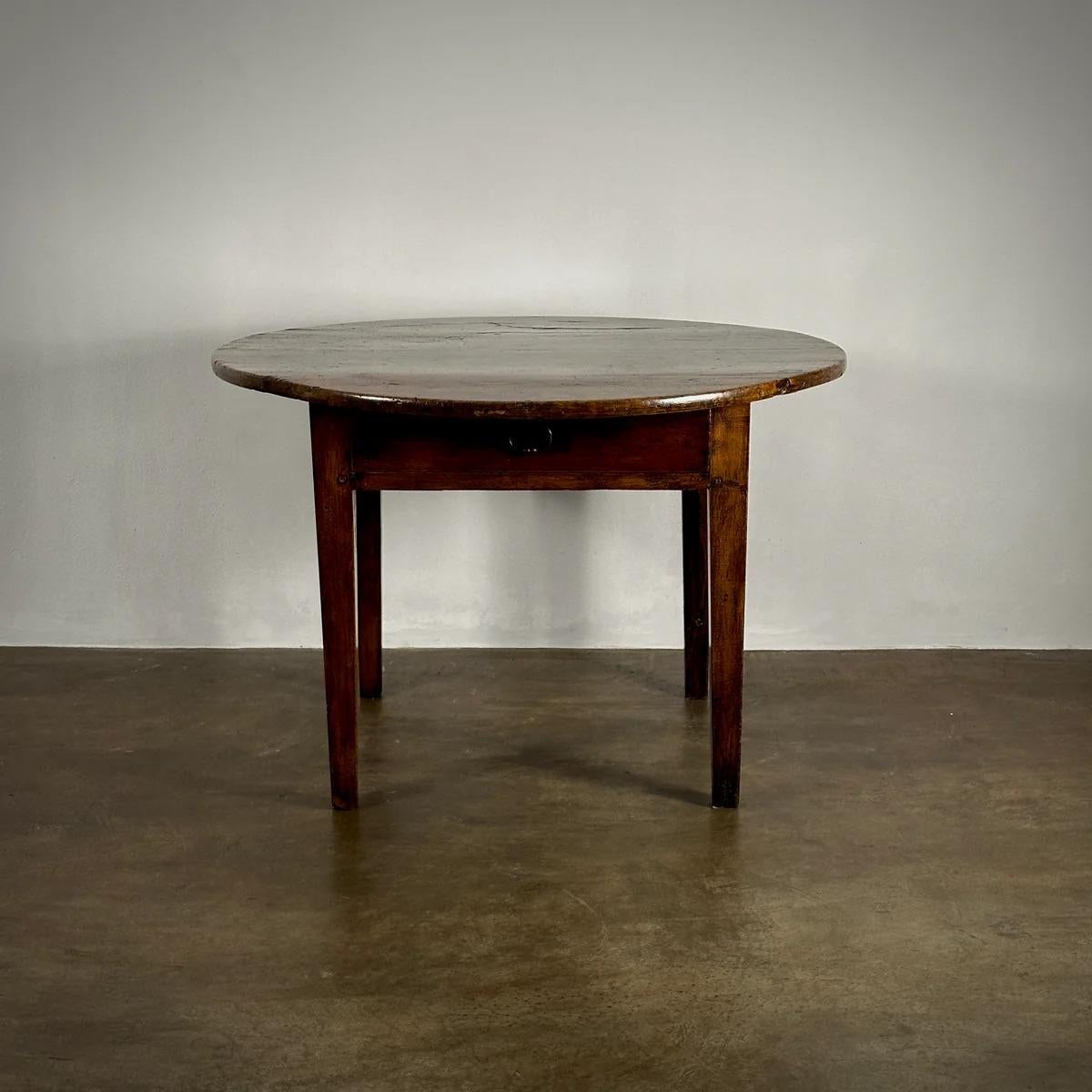 This rustic French oak center table exudes provincial charm with its circular top and straight, gently attenuated legs. The addition of a lower drawer offers practical storage, while the table's wonderful soft patina highlights its historical