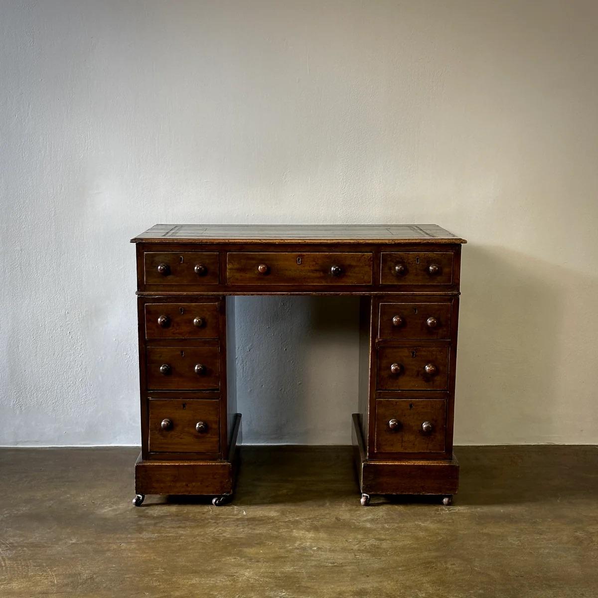 This distinguished leather-topped desk exudes classic Victorian charm. Constructed from sturdy walnut, it features ample storage with multiple drawers, each adorned with timeless round pulls. The rich patina of the leather and the warm tones of the