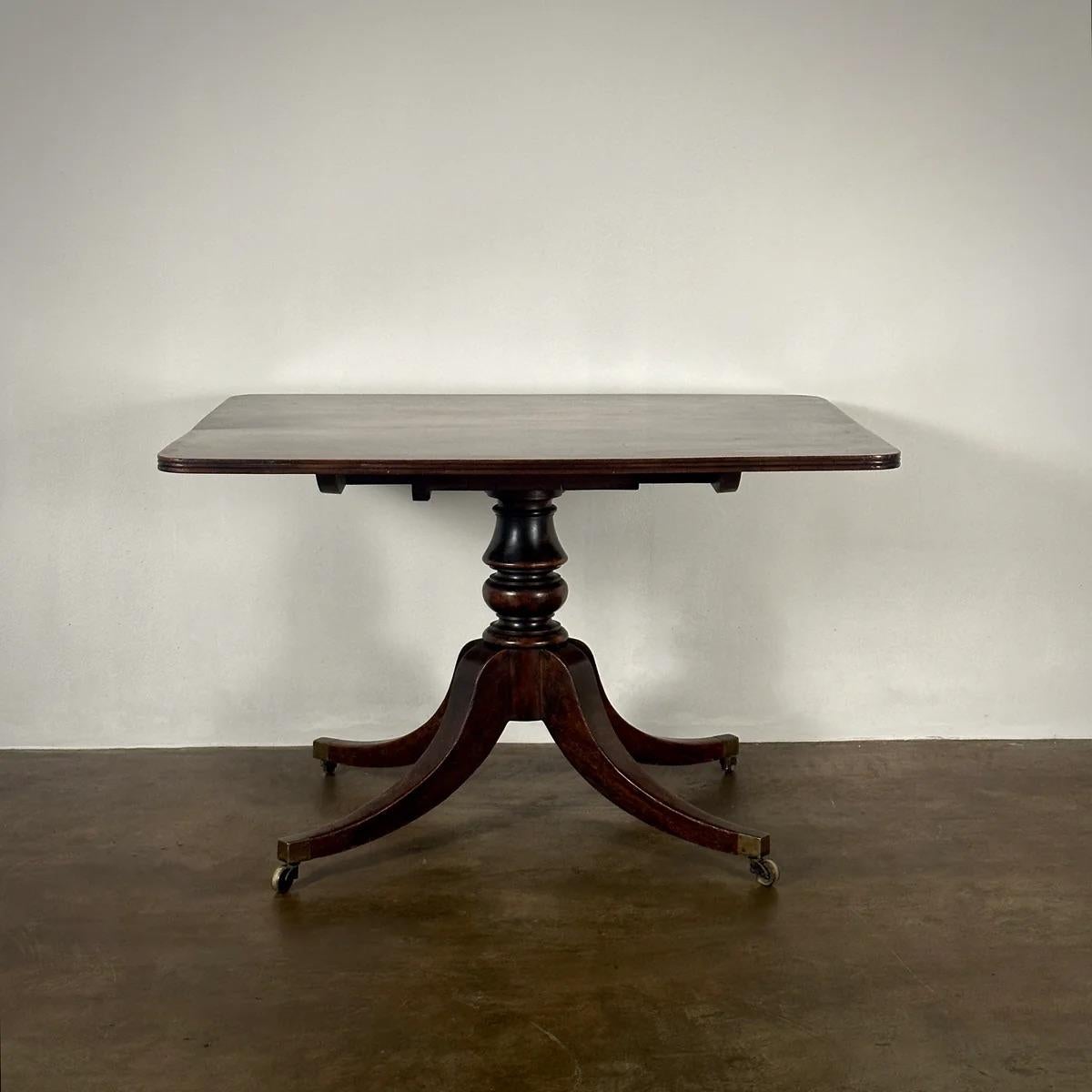 This elegant tilt-top breakfast table from England, circa 1860, combines functionality with historical charm. The table is crafted from rich mahogany, supported by a tripod base that features gracefully curving legs and original castors for